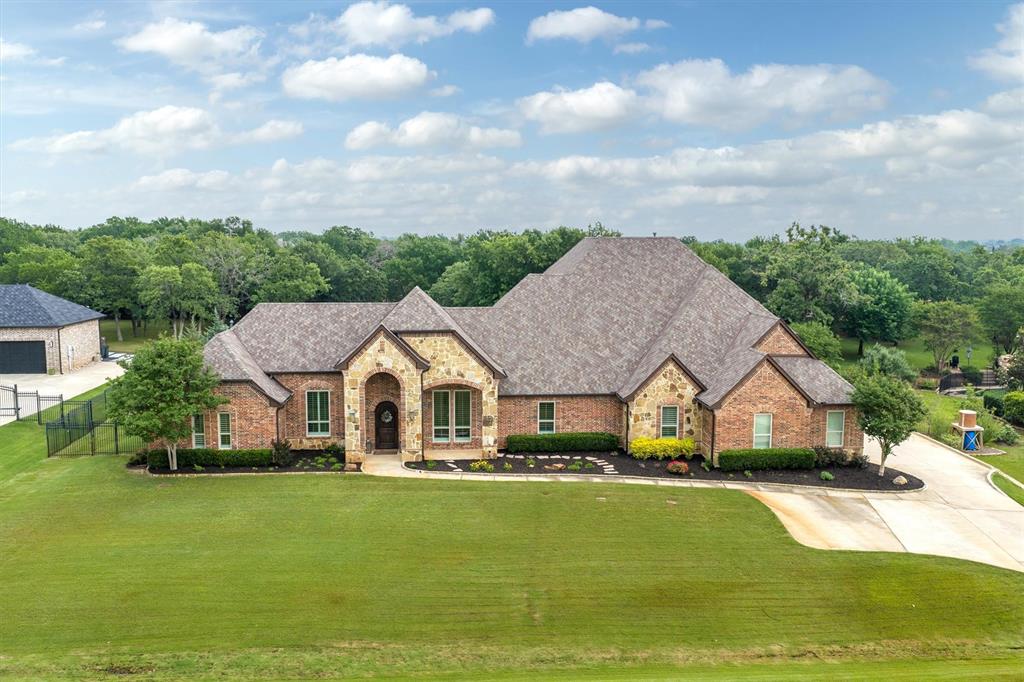 Welcome home to the heart of Double Oak, Texas! Nestled in a quiet neighborhood on one acre, this home offers an exceptional blend of space, style, and thoughtful design throughout. From the moment you step inside, you’re greeted with a view that draws your eye straight to the backyard oasis and sparkling pool. Designed for everyday living and effortless entertaining, the formal dining room is perfect for intimate dinners and special gatherings, while the dedicated home office provides a quiet and productive retreat. The living room, kitchen, and breakfast area serve as the true heart of the home, creating a warm and inviting space for family and friends to gather. The kitchen is a chef’s dream, featuring a spacious breakfast bar with seating for the entire family, a separate island, dual sinks, double ovens, sleek upper cabinetry with lighting, an updated backsplash, and honed granite countertops. A bright breakfast nook, along with a butler’s pantry and adjacent walk-in pantry complete with a pass through to patio area. The primary suite is a true sanctuary, complete with a beautiful stacked stone fireplace, picturesque windows, and a luxurious ensuite bathroom designed for relaxation. Downstairs, you’ll find two spacious secondary bedrooms connected by a Jack and Jill bathroom. One offers a hidden door that younger family members love! A separate guest suite with a full bath perfectly suited for poolside access. Upstairs offers incredible versatility for living, fitness, and entertainment, complete with a powder bath and cozy balcony with a fireplace, offering serene views of your live oak filled backyard. The outdoor living space is truly exceptional, featuring a large covered patio with a second outdoor fireplace, an outdoor kitchen, a huge diving pool, play set, and even a basketball court. This remarkable property seamlessly blends comfort, luxury, and functionality, and is ready to welcome you home.