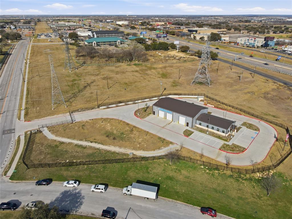 Built in 2025 and in like-new condition, this exceptional commercial office and warehouse facility sits on approximately 2.25 fully fenced and secured acres with outstanding I-30 frontage road exposure. The property offers excellent visibility and signage opportunities from both eastbound and westbound Interstate 30 traffic, with approximately 250,000 vehicles passing daily. The professionally finished office space includes approximately 1,800 square feet designed for both functionality and presentation. Features include a built-in receptionist desk and workspace with granite countertops, three private offices, a modern conference room with a glass wall and glass door, and a common open workspace with removable desks. The office also includes a kitchenette with cabinets, sink, and refrigerator, along with separate men’s and women’s restrooms.  The approximately 4,000 square foot warehouse is fully heated and cooled and offers 23-foot ceilings along with six electric overhead garage doors, including five 12-foot bay doors and one 14-foot bay door. The warehouse also includes its own restroom, making the space ideal for industrial operations, distribution, service companies. The site is fully gated and equipped with a security system and surveillance cameras, providing both security and functionality for a wide range of commercial or industrial users. Its modern construction, premium visibility, and highly functional layout, this property presents a rare opportunity for businesses seeking a turnkey commercial facility in a high-traffic corridor. Also for Lease $22-foot plus NNN