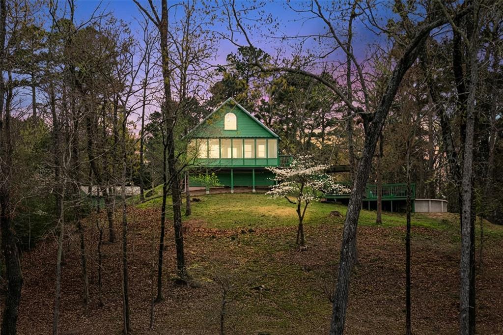 Perched on a scenic hilltop overlooking one of the Twin Lakes, this beautifully updated two story cabin offers privacy, elevated water views, and access to one of East Texas’ most peaceful lake communities. The home features two bedrooms, two bathrooms, and a versatile bonus space that could serve as a third bedroom.

Situated on 1.529 acres within the gated Gilmer Boating & Fishing Club, the property is surrounded by towering trees and park like grounds. Ownership also includes access to approximately two additional acres of shareholder maintained land, enhancing the sense of space. As a shareholder, you will enjoy access to both fully stocked Twin Lakes, shared by only 30 owners and their guests, ideal for fishing or relaxing under the community’s no wake policy.

Inside, the home blends rustic character with thoughtful updates. The kitchen offers granite countertops, stainless steel appliances, and generous cabinetry, while Satterwhite wood and blue wormwood accents add warmth throughout. A rock fireplace with gas logs anchors the main living area, and the layout flows easily for everyday living and entertaining. Additions completed in 2019, including the primary suite, laundry room, sunroom, and upstairs bedroom, expanded the space while maintaining the home’s cabin feel.

Outdoor living shines with a screened porch overlooking the water, a lakeside pool, and a separate Jacuzzi hot tub. A private fishing pier and fenced dog run add to the functionality.

Additional features include a workshop outbuilding with lean-to covered parking, Generac whole home generator with RV outlet, private filtered well, and gated concrete driveway.

With elevated views, access to both lakes, and a peaceful setting just minutes from Gilmer, this property is ideal as a full time home or weekend retreat.