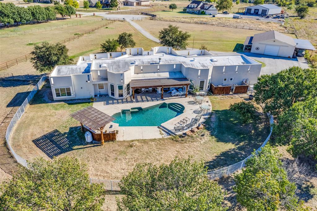 Horses welcome at this stunning 5.5-acre estate — a rare blend of sophistication and country living. This beautifully maintained property features cross-fencing, a renovated three-stall barn, and a spacious 1,728 sq. ft. pull-through workshop complete with a tack room — perfect for equestrian enthusiasts or hobbyists alike.

The Southwestern-style residence offers 5 bedrooms, 3.5 baths, and a dedicated office, all designed with comfort and flexibility in mind. The fifth bedroom ensuite, recently remodeled, offers endless possibilities as a guest retreat, in-law suite, or private second living area.

Inside, the fully renovated kitchen impresses with soft-close hickory cabinets, upgraded appliances, granite counters, an island centerpiece, and a generous walk-in pantry. The primary suite is a private escape, featuring an updated spa-like bath with dual vanities and a large walk-in closet. Even the utility room has been thoughtfully remodeled for modern convenience.

Step outside to your own backyard oasis — a newly renovated pool with a tranquil waterfall, shaded by a new pergola, and complemented by an outdoor kitchen with a built-in grill, perfect for entertaining under Texas skies. With a Generac generator providing up to five days of power, this property is as practical as it is picturesque.

5040 Wind Hill Court is more than a home — it’s a lifestyle. A must-see for those who dream of wide-open spaces, elegant comfort, and room to roam