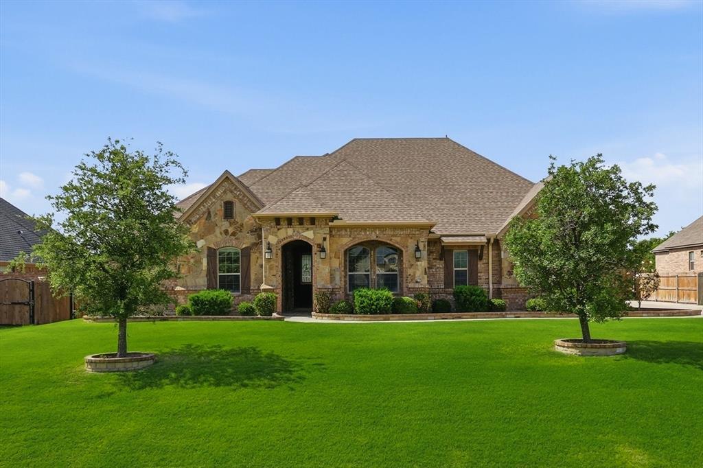 The fireplace on the covered patio gets more use than the one inside. Stone surround, ceiling fan, mounted TV. In North Texas, that's ten months of morning coffee, dinner outside, and evenings you don't want to end. That is if you can find the strength to leave your kitchen. Tuscan style stone-wrapped range alcove, granite island, bar seating, built-in wine rack, double oven, and wood beam accented ceiling. The dedicated home office opens with double barn doors and has its own closet. The main bathroom, with dual vanities, has a huge closet, walkthrough shower with dual heads and a soaker tub, for those days you need to unwind. And you haven’t even seen the true 3-car garage with an extended truck bay, spray foam insulation, hardwood floors, a huge half-acre yard, vaulted ceilings with wood beam trusses, and a floor to ceiling living room fireplace. Book your showing.