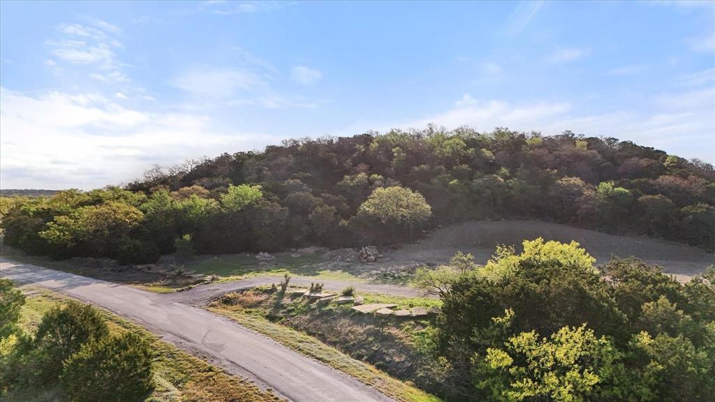 Breath taking views await you in the heart of Palo Pinto county. This is a perfect weekend get away on a wooded hill side with a great view of the beautiful rock landscaping throughout. Enjoy stunning sunsets each evening. a perfect way to unwind and take in the peaceful surroundings. This charming 2.556 acre secluded property sits outside of Mineral Wells and offers a unique blend of natural beauty and tranquility. Lovingly developed by its previous owners, the land features winding rock like trails that meander through the hillside. Don't be affaid of expanding your green thumb by putting beautiful flower beds and maybe a perfect outdoor fire pit that provides an ideal setting for a relaxing evening under the stars.Five minutes from the Brazos river and 20 minutes from Mineral Wells state park, this lot is ready for you to build your dream home from the ground up. Know that even with restrictions, manufactured homes, barndominiums, tiny homes and even brick homes will fit nicely in this perfect setting. Experience the quiet beauty of the Palo Pinto countryside. Don't miss your chance to own a slice of serenity.
