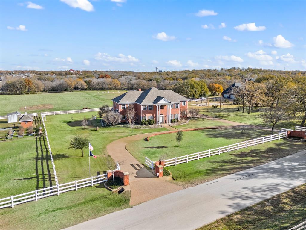 WHERE HERITAGE TREES MEET REFINED LIVING. Beautiful gated 8.6 acre estate, framed by century-old Post Oaks, offers refined country living with an agricultural exemption in highly sought after Argyle ISD. This exceptional hobby farm and equestrian property centers around an impressive 5,200 plus square foot home. Designed in a warm and timeless traditional style, the home blends classic architecture, elegant finishes and expansive living spaces that create a warm and sophisticated atmosphere. Rich wood tones, abundant natural light, and thoughtfully designed interiors provide comfort, character and functionality throughout. At the heart of the home, the kitchen opens seamlessly to multiple living and dining areas, ideal for entertaining or relaxed everyday living. The home features 6 spacious bedrooms and 4 bathrooms, including 2 with Jack-and-Jill layouts. The private primary suite serves as a peaceful retreat, while additional bedrooms offer flexibility for family, guests or home office needs.Outdoor, the fully fenced property is perfectly suited for horses, livestock, or a luxury hobby farm. Amenities include a 4 stall barn, deep water well with dedicated well house, sparkling pool, covered patio, and sport court.  Open pastures provide room for riding arenas and turnouts, scenic pond adds magic to the property. Majestic Post Oaks create a serene, park-like landscape.
The property currently benefits from an agricultural exemption offering potential tax advantages and supporting a variety of agricultural and livestock uses. Ideally located minutes away from Liberty Christian School, DFW International Airport, and the DFW Metroplex, this remarkable estate combines tranquility, convenience, elegance and the timeless beauty of Texas country living. Square footage per tax records, Buyer and Agent to verify schools, room sizes and AG exemption.