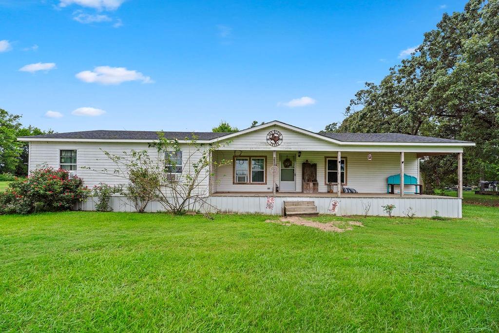 Welcome home to this beautifully updated 3-bedroom, 2-bath manufactured home offering approximately 1,740 square feet of comfortable living space. Close to Lake Fork !! Recent expansion in 2018 to create additional living area, this home combines spacious rooms with extensive recent improvements. A long covered front porch invites you in to sit and enjoy life on your own half acre. Step inside into a cozy living room that opens to the kitchen. The kitchen includes updated stainless steel appliances, including an electric range and dishwasher, plus breakfast bar. A spacious dining area leads to the second living space, an inviting hearth room that features a cozy wood-burning fireplace, creating the perfect gathering space for family and friends. 
The oversized primary suite provides a true retreat with plenty of room for a sitting area, a large 10' x 8' walk-in closet, an additional closet, and a beautifully updated ensuite bath featuring built-in shelving and an oversized glass-enclosed shower.
The split-bedroom floor plan offers privacy for everyone. Bedrooms two and three are generously sized at approximately 17' x 10' each and feature dual closets. A fully updated hall bath with a tiled shower and glass door is conveniently located between the secondary bedrooms.
Practical features abound, including a spacious utility room with washer and dryer connections, abundant shelving, and room for a freezer. Updates abound! Energy-efficient windows were installed in 2021. In August 2024, the living room and kitchen received fresh tape-and-bed work, enhancing the home's clean, updated appearance. Both bathrooms were completely remodeled in 2024, including updated plumbing, lighting, fixtures, and finishes. 
Gorgeous trees surround the property and open pasture views out the back side. Backyard is big enough for a garden or pool. Plus, features a carport for extra covered storage. Land is approximately 0.55 acres, to be determined by survey. 90 miles from DFW.