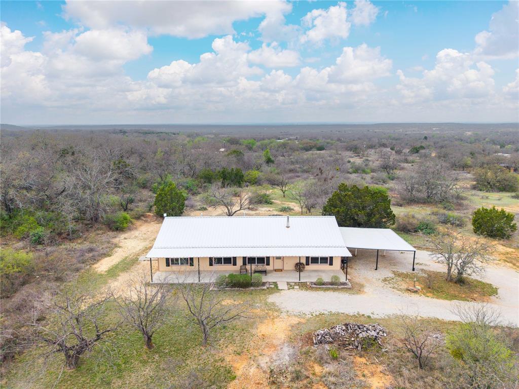 Atop a hill with breathtaking views that stretch for miles, this 3-bedroom, 2-bath ranch-style home sits on 60.85 acres of beautiful Central Texas land. The property offers privacy and security with a fully fenced perimeter and gated entrance, making it ideal for both a homestead and a recreational retreat. The home features a durable metal roof and a well-designed kitchen with pull-out drawers for easy access and organization. The propane tank is owned by the property owner, providing added convenience for future buyers. In addition to the home, the property offers excellent parking and storage options, including a two-car attached carport and a detached covered parking area large enough for two additional vehicles. Outdoor enthusiasts will appreciate the excellent hunting opportunities, two ponds, and generous tree coverage that attract wildlife & provide natural beauty throughout the property. According to the seller, the back portion of the land also contains abundant flint and fossils, offering a unique feature for those who enjoy exploring the land. Whether you’re looking for a peaceful country residence, a hunting property, or simply a place to enjoy wide-open Texas skies, this hilltop ranch offers privacy, space, and incredible panoramic views that are hard to find. CURRENT AG EXEMPTION