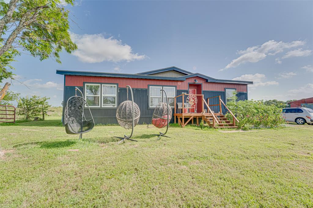 Experience peaceful country living in this beautifully designed 2022 doublewide situated on a spacious 2-acre lot. Enjoy privacy and room to roam, complete with a fenced area perfect for pets and an outbuilding ready for chickens or additional storage. Inside, the home features a modern open-concept layout with stylish designer finishes throughout. The expansive living area showcases decorative ceiling beams and recessed lighting, flowing seamlessly into a stunning kitchen. The kitchen is equipped with a large center island, stainless steel vent hood, electric cooktop, farmhouse sink, and warm wood cabinetry—ideal for both everyday living and entertaining. The private primary suite offers a relaxing retreat with an ensuite bath that includes a large walk-in shower and upgraded shower panel with body sprayers. A separate laundry room adds convenience, while durable luxury vinyl plank flooring throughout the home ensures easy maintenance and lasting appeal. Located in a quiet rural setting with convenient access to Hwy 24 for Commerce and I-30 for Greenville, this property offers the perfect balance of comfort, style, and accessibility.