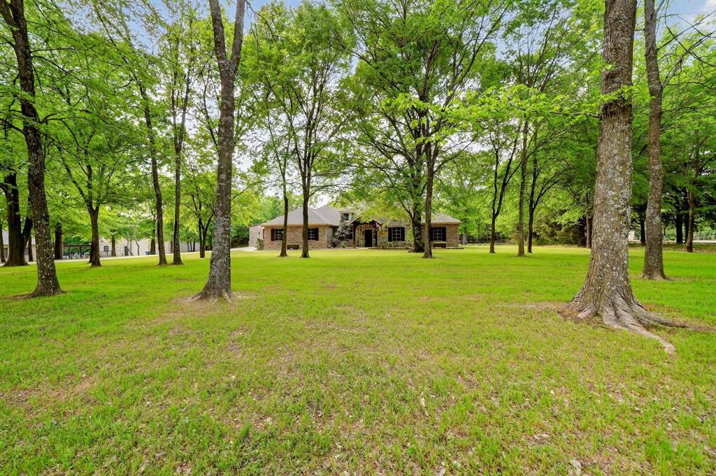 Luxury Country Living on 5+ Wooded Acres in the Highly Desirable Shadow Lakes Community! Welcome to 2211 Canyon Lake Rd, where privacy, recreation & resort-style living come together. This single-story home offers 3 bedroom, 2.5 baths, a dedicated office & 2,554 sq ft of open-concept living designed for both everyday comfort & entertaining. Inside, you'll find custom cabinetry, granite countertops, ceramic tile flooring throughout & LED can lighting. Energy-efficient upgrades include radiant barrier attic decking & SunTex solar screens. Step outside to your own private retreat featuring a stunning heated saltwater pool & spa installed in Summer 2024, complete with waterfall, tanning ledge, bubblers, LED lighting & app-controlled operation. The outdoor living area includes a fully equipped kitchen with grill, refrigerator & storage, plus a second covered patio anchored by a beautiful stone fireplace, creating the perfect space for year-round gatherings. The 30x60 shop with two 12x10 roll-up doors & a bathroom offers ample room for boats, ATVs, side-by-sides, equipment, hobbies, or a home business. Additional features include an oversized garage, wrought-iron fenced backyard with double-gate access, mature trees, beautiful landscaping, a small pond, 4K security cameras & custom Christmas lighting. For outdoor enthusiasts, this property is hard to beat. Residents of Shadow Lakes enjoy access to multiple lakes, private ponds, fishing, hunting, hiking trails, abundant wildlife & endless opportunities to enjoy the outdoors. Whether you're casting a line at sunset, exploring the trails, hosting friends by the pool, or simply enjoying peaceful evenings under the East Texas stars, this property offers a lifestyle few homes can match. Conveniently located just minutes from Hwy 20, this turn-key property combines luxury outdoor living, wooded acreage, community amenities & an exceptional shop in one remarkable package. More than a home—it's your private East Texas retreat.