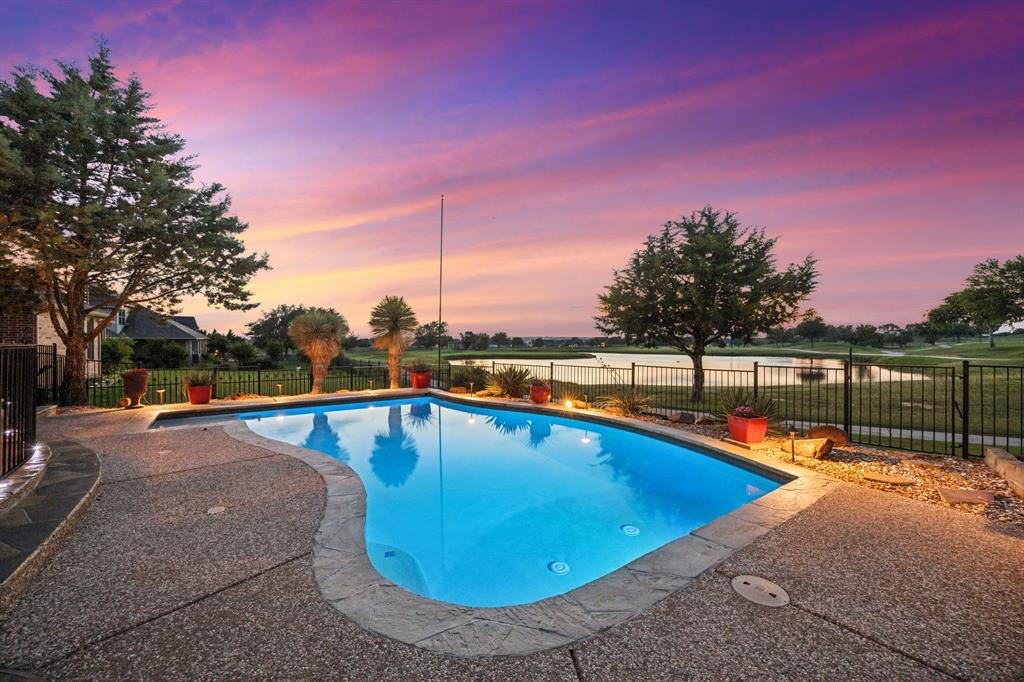 Welcome to luxury living in The Resort on Eagle Mtn. Lake, the area's only 24-hour gated and guarded golf course and lakefront community. Perfectly positioned on the 18th hole, this stunning custom home offers breathtaking views of the golf course and pond, creating stunning views you'll enjoy every day. From the moment you arrive, you'll be impressed by the beautifully landscaped grounds with custom lighting in both the front and backyard. Inside, rich hardwood floors, soaring ceilings, and an open-concept design create an inviting atmosphere ideal for everyday living and entertaining. The spacious chef's kitchen serves as the heart of the home, featuring an oversized island, gas cooktop, abundant cabinetry, and seamless flow into the living and dining areas. With five generously sized bedrooms, this thoughtfully designed floor plan offers two bedrooms on the main level. Upstairs, you'll find three additional bedrooms, a dedicated theater room, and an expansive game room providing plenty of space for family and guests. The oversized primary suite is a true retreat, showcasing stunning golf course views, a luxurious en-suite bath, and a large walk-in closet. Step outside to your private backyard oasis complete with a heated pool, custom outdoor fireplace, and outdoor kitchen featuring a built-in gas grill—perfect for year-round entertaining. Additional upgrades include dual-fuel heat pumps, a backup generator, surround sound system, and countless custom features throughout. Enjoy resort-style living with exceptional community amenities, including an 18-hole golf course, clubhouse with pro shop, restaurant, bar, fitness center, two community pools, playground, pickleball and basketball courts, plus a private beach area with pergolas, boat slips, and a boat ramp providing easy access to Eagle Mtn. Lake. Conveniently located just 30 minutes from DFW Airport and downtown Fort Worth, this home offers the perfect combination of luxury, recreation, and accessibility.