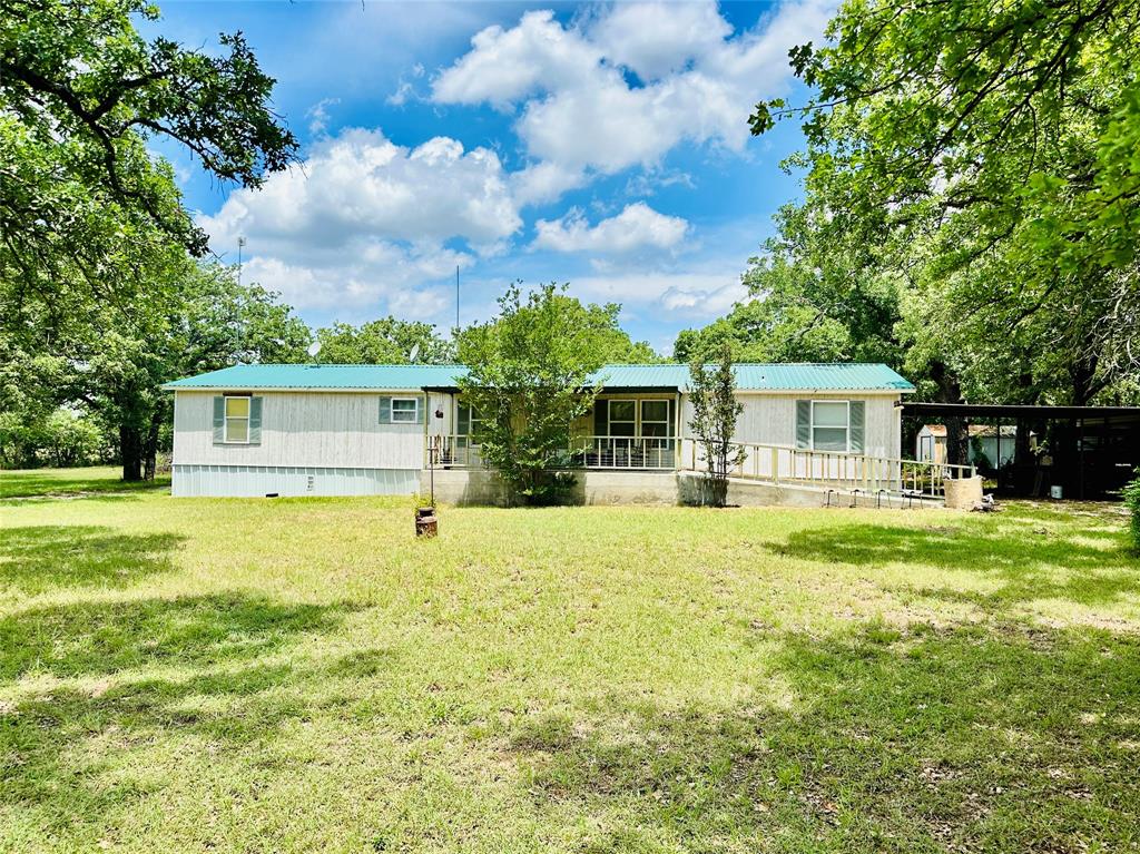 Great set up for having some livestock and living in the country while being close to town.  This 4.5 acres is only minutes from Cross Plains and has a beautiful front yard with scattered Post Oaks and a more heavily wooded back pasture (1.5 acres) which is fenced from the house.  The 1,904 sq ft 1997 built, 4 bedroom 2 bath mobile home has been remodeled with laminate wood floors throughout common areas and carpet in the bedrooms.  The home has a split floorplan with the primary suite on the west end and all 3 guest bedrooms and hall bath on the east end.  The open concept living, eat-in kitchen and dining are great for entertaining or family gatherings.  The kitchen has recently painted cabinets and granite-look Formica countertops with a single basin stainless sink, stainless appliances and an island looking into the living room.  The primary bath has a corner garden tub, ceramic tile shower, dual sinks, linen closet and attached walk-in closet.  The hall bathroom has a tub shower insert. The utility room has full size laundry area as well as extra room for either a freezer or a drying & folding area for clothes.   
The home is supplied by Coleman SUD water and buried electric lines.  There is a 20x20 carport beside the house and a small storage building in the backyard.  I can't say enough about the trees around this house and the seclusion you feel while you are there.