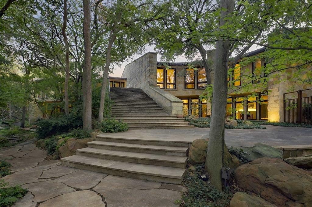 In a neighborhood where architectural distinction defines the landscape, stands a 14,921 square-foot estate with an additional 2,378 square-foot attached natatorium that challenges every notion of residential design. 

Conceived as a nautilus shell with wedge-shaped rooms that radiate outward from a dramatic central elevator, Michael Murphy’s masterpiece at 5110 Park Lane represents a rare achievement in domestic architecture.

This unique configuration offers spectacular views from every room while simultaneously cultivating an intimate, tree house-like feeling of being suspended within the surrounding canopy of mature trees. 

Set on lush grounds featuring a meandering creek, rolling terrain, and dense foliage, the residence achieves complete integration with its natural surroundings. The extensive use of warm-toned Lueders limestone — quarried in Texas specifically for this project — creates seamless transitions between interior and exterior spaces. 

The upper level houses the primary living quarters, where buffed concrete floors, Venetian plaster walls, and limestone form a cohesive interplay of texture & tone. Three bedrooms anchor the main residence, complemented by two additional bedrooms within a separate guest apartment that ensures privacy while maintaining stylistic integrity.

The lower level elevates two-story living into something extraordinary. Here you'll find sophisticated office spaces, media rooms, conference areas, and recreational amenities including a workout room and stunning lap pool with a fiber-optic waterfall feature. 

Preston Hollow's coveted location provides immediate access to Highland Park Village & Inwood Village, top private schools, and Love Field Airport, connecting residents to both neighborhood amenities and the broader metroplex.
