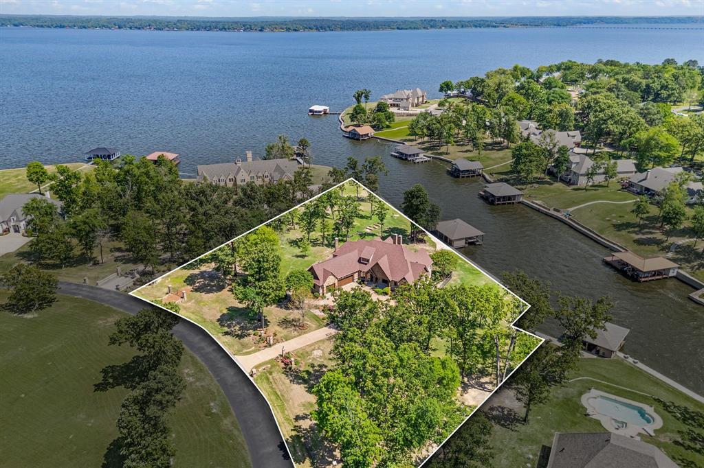 Welcome to Brown's Landing, an exclusive gated community nestled in Lake Palestine. This stunning estate encompasses 2.1 acres, featuring 442 ft of shoreline that provides immediate access to open waters while offering the serenity of a cove. Say goodbye to extensive maintenance associated with open-water homes; this property perfectly blends the joys of lakeside living w comfort of a protective cove. Step inside, you are greeted by bright & airy living area that boasts soaring vaulted ceilings & elegant design elements. Cozy fireplace invites you to unwind during chilly evenings, creating warm & inviting atmosphere. Open floor plan promotes seamless flow between living space, formal dining rm, & gourmet kitchen, which is highlighted by oversized island ideal for entertaining guests. Picture sipping your morning coffee on your covered patio, warmed by wood-burning fireplace, while soaking up breathtaking sunrises. Versatile bonus rm with captivating views is perfect for family meals or lazy afternoons. Primary suite is spacious sanctuary boasting impressive bathrm w coffee bar & private access to backyard. Thoughtfully designed lower level is entertainer’s dream, featuring extra living area w fireplace, game rm w pool table, bar for mixing up your favorite drinks, & media rm w updated Full Swing golf simulator for year-round fun! The home comfortably sleeps 10+ guests ensuring ample space for family gatherings, weekend getaways, or entertaining friends. Your 3-stall boathouse w stunning Garapa Brazilian hardwood deck & freshwater access is ready for fishing, boating, & skiing. The extraordinary home blends luxury & comfort featuring newly upgraded Crestron home automation system, Hickory wood flooring, Generac Whole House 36KW backup generator, & 2 buried propane tanks (1000 & 500). Visualize your new lifestyle & endless possibilities that await with virtually staged images, showcasing the potential of this exquisite property. This property is truly one-of-a-kind!