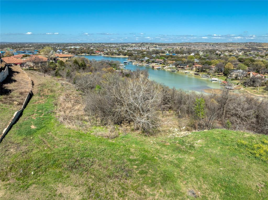 Now offered at an improved price, this uniquely private lot showcases stunning panoramic views of Eagle Mountain Lake, including breathtaking sunrises and sunsets. Spanning nearly one-third of an acre at the end of a cul-de-sac, the property offers an exceptional setting for your dream retreat. Terraced greenspace with mature trees leads toward the water, creating a beautiful natural backdrop. The elevation is ideal for a two-story new build with a walk-out basement and rear-facing rooms designed to capture the lake views. With ample space for recreation and relaxation, the lot is build-ready and perfectly suited for boating, fishing, or simply enjoying the peaceful surroundings. The property backs to the lake, includes nearby walking trails, and offers lake access through the Lake Country community dock for boat launches. Private, serene, and surrounded by natural beauty, this rare Eagle Mountain Lake lot blends seclusion with luxury—an opportunity you won’t want to miss.