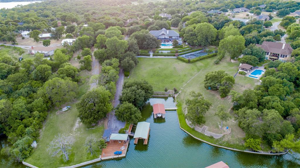 This Eagle Mountain Lake Estate includes a spectacular home with over 5300' air conditioned sq ft under a new roof & gutters installed Spring 2025, 4 bedrooms, 3.5 baths, a swimming pool, cabana, tennis-basketball-volleyball sports court, children's overnight playhouse, a field perfect for a game of touch football or soccer, wooded hiking areas, go-cart riding roads, vegetable garden, separate garage-workshop, boat dock, jet ski lifts and more variety of shade trees, flowering trees, and native trees than you can count on both hands! Wow, that's a property full of Blessings. All this for $2,449,000! This property sits on 3.5 lush acres. The water at the dock is almost 9' deep (when the lake is full) and is located on one of the deepest sloughs on the whole lake. A 5-minute drive to the nationally known Fort Worth Boat Club. With a Doctor on one side and a Pastor on the other, can it get any safer and more secure than that?!  Come explore and Discover Additional Benefits Hidden in Plain Sight for this property is as sweet as 'TUPELO HONEY'.