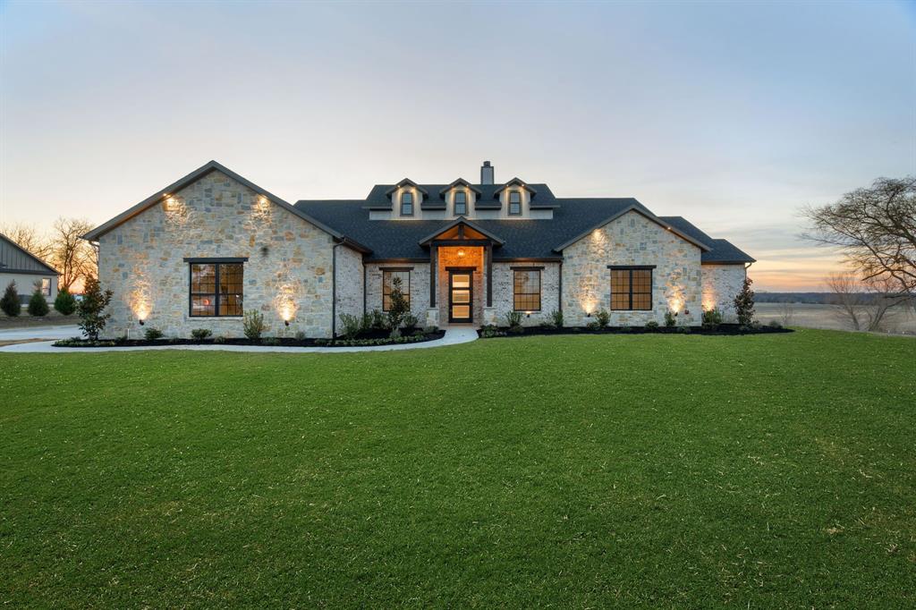 BUILDER IS OFFERING $5,000 IN CLOSING COST ASSISTANCE WITH AN ACCEPTED OFFER!!
Indulge in refined country elegance with this exceptional custom-built estate, gracefully positioned on 2.6 picturesque acres in Farmersville, Texas. Designed with both sophistication and comfort in mind, this remarkable residence offers privacy, expansive living, and breathtaking sunset views.
A striking stone facade and grand covered entry create a lasting first impression, setting the tone for the elevated design found throughout the home. Inside, soaring vaulted ceilings with architectural detail and a dramatic floor-to-ceiling stone fireplace anchor the main living space, creating a warm yet impressive focal point. Expansive windows frame serene countryside views while flooding the interior with natural light, enhancing the home’s airy and open ambiance.
The thoughtfully designed floor plan includes a private executive office with closet, offering the flexibility to serve as an additional bedroom. The gourmet kitchen is a true showpiece, featuring extensive custom cabinetry, quartz countertops, a generous island ideal for gathering, and a spacious walk-in pantry designed for both beauty and function.
The primary suite is a luxurious retreat, complete with private patio access, a custom oversized walk-in closet, dual vanities, a spa-inspired walk-in shower, and an elegant soaking tub designed for ultimate relaxation.
Home offers upgraded patterned carpeting, with two bedrooms offering private ensuite baths for elevated comfort and privacy. A well-appointed powder bath near the laundry room provides convenience for guests.
Additional highlights include energy-efficient spray foam insulation for year-round comfort and long-term savings, tankless water heater, gorgeous landscape, extended concrete driveway as well as refined finishes throughout.
This gorgeous custom home offers the perfect blend of luxury, tranquility, and modern 
Functionality! Schedule a showing today!