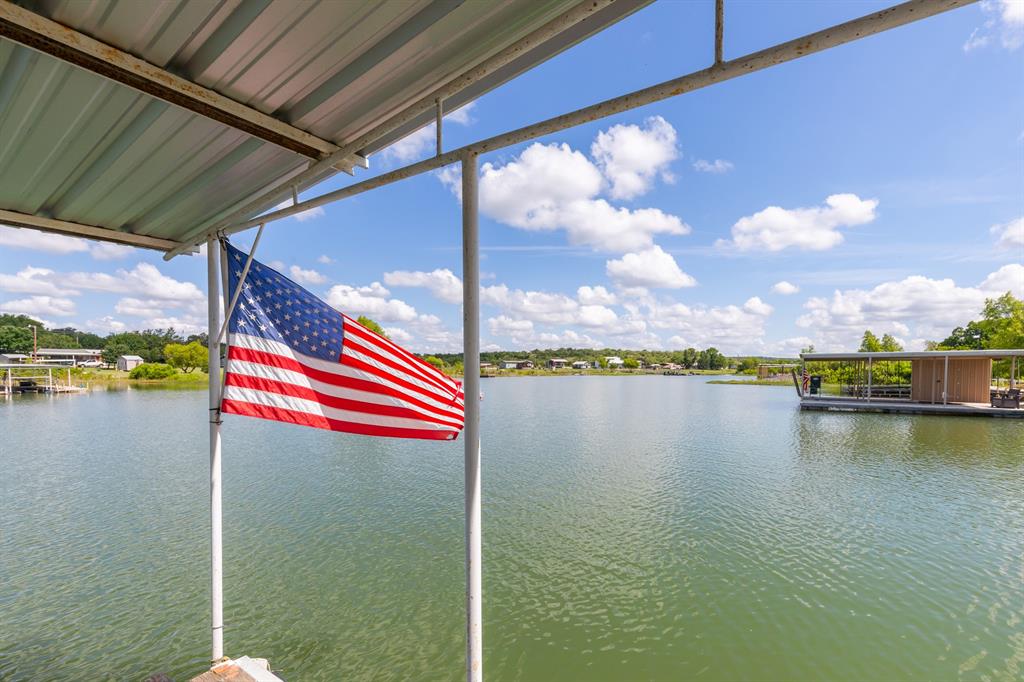 Turn-Key Lakehouse. Fully furnished and ready for you to relax the rest of the year away. There’s no need to escape when the lake is your primary residence. This home would also make a great second home or Airbnb with its always happy vibe of color and scenery. Enjoy picnics on the covered back porch, on the boat dock, or in the lush Saint Augustine grass beneath two large pecan trees. This 4-bedroom, 2-bathroom home features a split floorplan, with LVP in the kitchen and dining room installed in 2022. The carpet is upgraded—not original—and the HVAC unit was replaced about six years ago. The metal roof on both the house and the boat dock was replaced in 2024, which sounds like lower insurance rates. Thoughtfully covered parking near the front door keeps you out of the elements. The kitchen window, perfectly positioned to frame the serene landscape of water, was a primary focus when placing this home exactly where it sits. A lake pump is already in place to water the backyard, and the dedicated laundry room has space for an additional fridge. When holidays and events come around, the large neighborhood community of Lake Coleman is a special place to be. You’ll want to spend each night watching the sunset from your back porch—another intentional highlight of the home—with room for many chairs, coffee tables, and still plenty of space for games and activities. A chain-link fence keeps pets nearby. Down the steps by the concrete retaining wall is a patio picnic area and a private boat ramp you can use right on your own property. You'll want to come tour this home soon. Lake Coleman is currently 87% full. You’re just 21 minutes from the town of Coleman, 33 minutes from Cross Plains, and 41 minutes from Tuscola and 47 to Abilene.