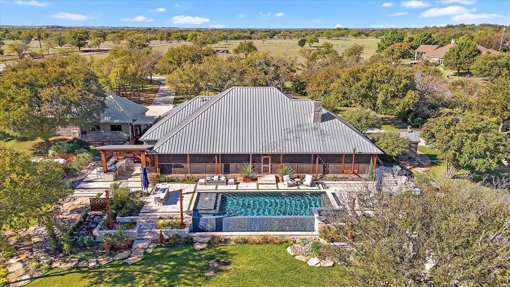 Introducing 5-Four Ranch — a premier 54-acre luxury estate offering rare privacy, intentional design, and an elevated ranch lifestyle just minutes from Denton and Rayzor Ranch. Built by renowned custom homebuilder Kent Key and professionally interior-designed, this incredibly stunning 3,512 square foot residence blends refined western influence with modern desert tones, curated finishes, and expansive native views. Most furnishings—primarily Restoration Hardware pieces—may be purchased separately to create a seamless turnkey experience.

The chef-inspired kitchen offers exceptional quality with a Thermador 48-inch dual-fuel range with double ovens, Sub-Zero commercial-grade glass-front refrigerator, custom soft-close cabinetry, honed quartz countertops, dual sink stations, a dedicated coffee bar, and an ASKO Dishwasher.

Floor-to-ceiling windows extend across the back of the home, opening to a 900 square foot screened outdoor living veranda complete with Chicago brick flooring. A resort-style infinity-edge sport pool and twelve-person spa, designed by award-winning HGTV pool designer Mike Farley and enhanced with two Tuuci Umbrellas, anchors the outdoor experience.

Natural stone steps reclaimed from the property—embedded with fossils estimated to be over ten thousand years old—lead to a dramatic fire-pit terrace featuring a converted six-foot steel cauldron, creating an unforgettable sunset gathering destination.

The acreage is fully fenced and cross-fenced with pipe and wire and includes improved pastures, mature trees, longhorn views, a barn, and a custom gated entry. A fully climate-controlled 2,205 square foot detached garage with gym adds generous flexibility for vehicles, storage, and equipment.

With private well, septic, and no HOA, this exceptional North Texas estate offers both independence and convenience. More than a property, 5-Four Ranch is a place to live beautifully, entertain effortlessly, and create a lasting legacy.