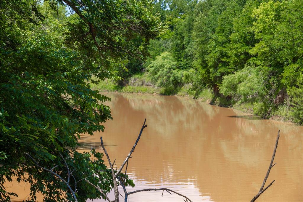 Discover the perfect blend of privacy, recreation, and opportunity with this exceptional property offering everything you could want in a dream homesite or weekend getaway. Whether you’re looking to build your forever home, create a private hunting and fishing retreat, or simply escape to the country to ride ATVs and enjoy the outdoors, this remarkable acreage delivers endless possibilities. Conveniently accessible from two roads, including frontage along FM 585, the property welcomes you through the gate with breathtaking rolling elevation changes and scenic views throughout. At the heart of the land sits a large picturesque pond, creating an ideal setting for fishing, wildlife watching, or relaxing by the water. The property also boasts frontage along the Love Branch of the Jim Ned River, adding both beauty and recreational value. A mix of open areas and heavily wooded sections provides the perfect balance of usable land and privacy, attracting abundant wildlife and offering excellent hunting potential. Multiple locations throughout the property already have access to electricity, and rural water is available, making it easy to choose your ideal build site. With its size, layout, and multiple access points, this property also offers outstanding investment potential. Whether you choose to keep it as one private ranch or explore opportunities to subdivide and maximize value, the possibilities are endless. Rarely do properties combine natural beauty, recreational appeal, building potential, and investment opportunity in one package. Come experience the peace and versatility this incredible property has to offer before it’s gone.