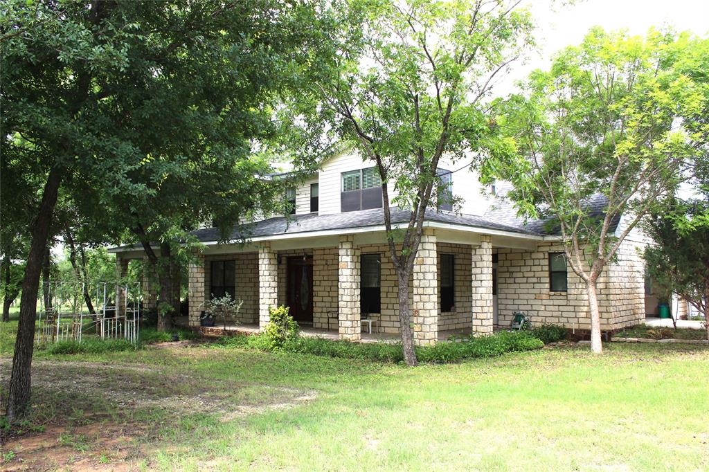 Beautiful 3315 SF 2 story Austin Stone Home situated on 2 wooded acres with paved road frontage 1 mile from Lake Proctor.  This property has lots of wildlife and has a beautiful, quiet, peaceful sitting.  The home features 5 (or 6) bedrooms, 3 baths, dining room, media room and has the open concept with soaring ceilings. The home has large porches, beautiful mature trees, a RV shed with power, 2 heat pump units.  On the ground floor you will find the master suite with  large walk-in closet, jetted tub, and separate shower.  The 2nd bedroom is downstairs with an adjacent full bath.  Upstairs there is 3 more bedrooms, a full bath, and an oversized media or game room that could be a 6th bedroom.  This home is vacant, easy to show, and ready for a new family.  There is an additional 27.5 acres that can be purchased all or partially with the home.  With more acreage there is a pond, improved variety pecan trees and coastal grass.  Lots of income potential here.  Proctor irrigation valves are on the acreage.  Look today and you will be impressed. Seller will give a $5,000. carpet allowance.