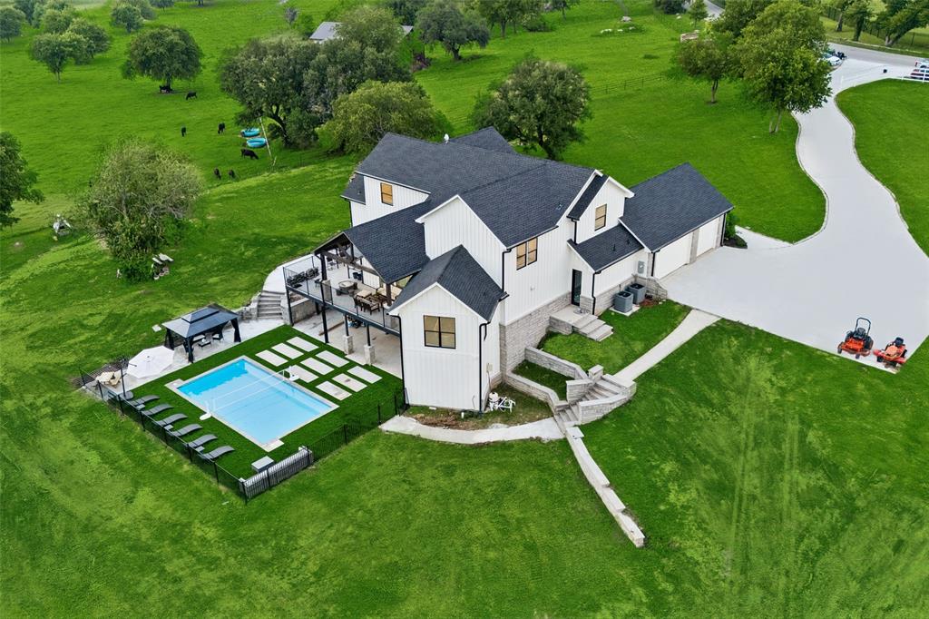 Experience refined Fort Worth living in this exceptional estate set on more than 19 acres, offering space, privacy, and endless potential. With 5 bedrooms and 6 baths, this thoughtfully designed home delivers a versatile layout suited for both everyday living and entertaining. The main level is filled with natural light and elevated by designer finishes throughout. A spacious living area with vaulted ceilings and expansive windows creates a warm, inviting atmosphere. The well-appointed kitchen features a large island with seating, built-in stainless steel appliances, generous prep space, and abundant storage, along with a bright breakfast nook for casual dining. The primary suite on the main level provides a peaceful retreat, complete with a spa-inspired bath designed for comfort and relaxation. An elegant home office offers a quiet and functional workspace. Upstairs, additional bedrooms and baths provide flexibility for a variety of living arrangements. The lower level expands the home’s possibilities with space ideal for recreation, fitness, or gatherings, including areas suited for a game room, media space, or home gym. Outdoor living is equally impressive, featuring a patio and balcony for relaxing or hosting, along with a beautifully designed pool and gathering area that takes full advantage of the surrounding acreage. A three-car oversized garage adds convenience and storage. Set on more than 19 acres, this property offers a rare opportunity to enjoy expansive surroundings with room to personalize and create your vision. Video and 3D tour is available! Includes: JOHN KISER, SURVEY ABSTRACT 917 TRACT.