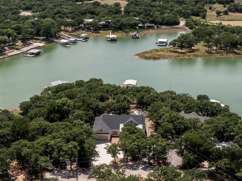 Experience lakeside living at its finest in this beautiful waterfront home on Lake Bridgeport!  Built in 2022 by Hedgefield Homes, this 4 bedroom 2.5 bath property is situated on a half acre lot with 136 feet of water frontage and offers breathtaking water views from the moment you walk inside.
The thoughtfully designed open concept floor plan features split bedrooms for added privacy, quartz countertops throughout, custom window shades, and a spacious primary suite with large walk in closet. The kitchen is beautiful and well equipped with center island that seats 3, stainless steel appliances and windows that bring in natural light and gorgeous lake views.  The oversized walk in pantry, laundry room and mud room are fabulous amenities that this well designed home offers.  Outside, you’ll enjoy lakeside living year round from the covered back porch and spacious backyard.  There is also a slab already in place that is an open slate for whatever type of outdoor oasis you may want to create!  The gently sloping lot with stone walkway provides easy access to the lake, where you'll find a private boat dock complete with a 6,000 lb boat lift.  Additional features of the property include an insulated two car garage, sprinkler system, 3,000 gallon water storage tank, and an advanced filtration system that allows you the flexibility to use either fresh water delivery or treat water drawn directly from the lake.  This exceptional waterfront property is located in a quiet, calm cove and combines modern comfort, quality construction, and stunning lake views to create the ultimate Lake Bridgeport retreat!