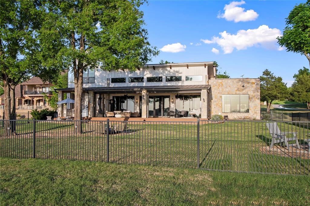 Welcome to your dream lakefront escape in The Bluffs, a prestigious gated community on Cedar Creek Lake. Situated on a beautifully landscaped ¾ acre lot, this modern retreat blends natural materials like stone, wood, and iron to create an inviting, luxurious atmosphere. Inside, the home is bathed in natural light thanks to soaring wood beamed ceilings and a dramatic wall of windows framing picturesque lake views. The chef’s kitchen is a true showstopper, featuring a professional Thermador propane gas range, island seating, farmhouse sink, built-in ice maker, and a striking glass door wine cellar, perfect for entertaining. Genuine hardwood floors flow throughout, leading to a first floor lakeside primary suite with wood beam ceilings and spa like ensuite bath offering dual vanities, a walk in shower, and a relaxing soaker tub. Three more additional guest bedrooms, two with built in bunk beds for added flexibility. Outdoor living is just as impressive, with multiple entertainment areas designed for true lake life. A large covered composite deck with automatic screens provides the ideal setting to enjoy the view, mosquito free. The wrought iron fenced yard is perfect for kids and pets, while the private boathouse includes automatic lifts and covers for both a boat and personal watercraft, making lake access effortless. Residents of The Bluffs enjoy a waterside clubhouse, community firepit, and picnic areas. Located in a prime spot on the lake once  home to a waterski school, this area is beloved for its smooth waters, fishing, and recreational fun. Watercraft available separately.  Additional boat slip in community marina available for $55,000.00.