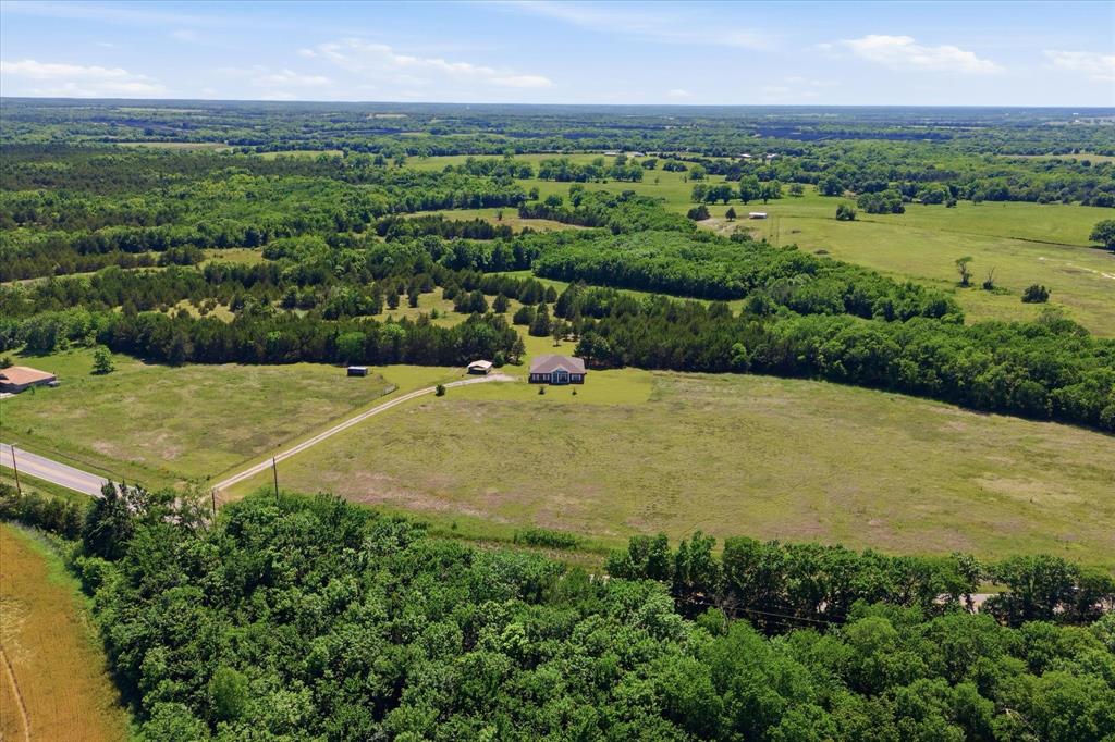 Listed at appraised value! Tucked beneath wide TX skies and surrounded by peaceful acreage, this Bonham retreat is the kind of property people spend years hoping to find. The moment you pull down the long driveway, life slows down a little, the air feels different and suddenly, home means something more. Set on 20.2+ acres of countryside, just minutes from Bonham State Park, this beautifully maintained single-story brick home offers the rare balance of comfort, privacy, and freedom. Mature trees frame the property, open green space, and trophy-style Texas native wildlife create a true private ranch-like atmosphere. A picturesque pond is the perfect backdrop for simply watching the sky's reflection roll across the water. Inside, the home was designed for real living. The open-concept layout brings everyone together with an eat-in kitchen, spacious living areas, and a warm, welcoming feel throughout. The kitchen serves as the heart of the home with granite countertops, an oversized island, abundant cabinetry, and the kind of space that naturally becomes the gathering place during holidays or slow Sundays. The primary suite offers a peaceful escape, while the 3 additional bedrooms provide flexibility for family, guests, hobbies, or a home office. Tile flooring, walk-in closets, and thoughtful finishes make the home both functional and comfortable. With no HOA and room to breathe, this property invites a lifestyle many buyers crave but rarely find. Bring the animals, build the workshop, start the garden, park the toys, or simply enjoy the quiet privacy that comes with owning acreage outside city limits. The covered back porch becomes your front-row seat to Texas sunsets, star-filled skies, and mornings where the only sound is the breeze moving through the trees. This is more than a home. It’s the kind of property that clears your mind and reminds you what living in Texas is supposed to feel like. Only an hour from downtown Dallas, this makes the perfect country home.