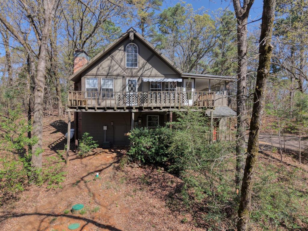 Tucked beneath a canopy of mature trees, this charming cabin-in-the-woods retreat offers peaceful surroundings and natural beauty on a 0.43-acre lot. This inviting 2-bedroom, 2-bath home, plus sleeping porch, a 1-car garage and approximately 1,224 square feet captures the warmth and character buyers love in a woodland getaway while providing comfortable everyday living.

The welcoming living area features a cozy atmosphere with natural light filtering through the trees, creating a relaxing space to unwind or gather with friends and family. The layout flows easily into the kitchen and dining areas, offering a functional design with great potential to personalize and make your own.

Both bedrooms provide comfortable space and privacy, while the two full bathrooms add everyday convenience for residents and guests alike. The thoughtful floor plan balances functionality and charm, making the home ideal as a full-time residence, weekend retreat, or peaceful escape from the busy pace of life.

Step outside and enjoy the beauty of the spacious wooded lot, where towering trees and natural surroundings create a sense of privacy and tranquility. The outdoor space offers room to relax, entertain, garden, or simply enjoy the quiet sounds of nature. Imagine morning coffee on the porch, evenings under the trees, and the peaceful lifestyle that comes with cabin-style living.

The one car garage provides practical storage and parking, while the generous lot size allows additional space for outdoor enjoyment.

Properties that combine rustic cabin charm, a large wooded lot, and a serene setting are increasingly hard to find. This home offers a wonderful opportunity to enjoy the beauty of East Texas living while adding your own personal touches.

Come explore the possibilities and experience the peaceful setting this inviting woodland retreat has to offer.