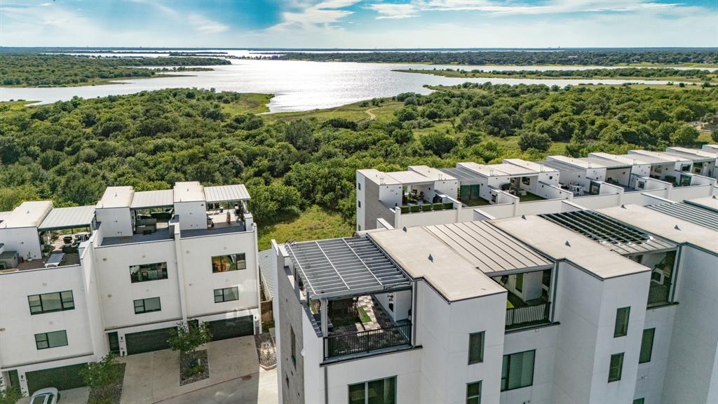 Not every buyer is searching for a traditional home. Some are searching for something extraordinary. Perched above Lake Lewisville in the sought-after Westport Lakeview Villas community, a 4 story residence offers a lifestyle rarely found in North Texas. Combining modern architecture, soaring 12ft ceilings, private elevator access, and breathtaking lake views from multiple levels, this home feels more like a luxury waterfront retreat than a traditional townhome. Unlike many homes in the community, this premium location enjoys a rare unobstructed sightline through the front row of villas, creating stunning water views from the living spaces, upper levels, rooftop terrace, and even the primary suite. Wake each morning to peaceful lake views and enjoy spectacular sunsets year-round from the primary suite, kitchen, living areas, and rooftop terrace. Designed for both everyday living and effortless entertaining, the open-concept floorplan, filled with natural light and elevated finishes throughout. The chef's kitchen features premium Thermador appliances, sleek contemporary design, generous storage, and seamless flow into the dining and living areas. A built-in bar creates the perfect setting for hosting guests, while expansive windows frame the lake beyond. Technology and convenience are seamlessly integrated throughout the home with a fully connected smart-home system that allows control of lighting, automatic shades, televisions, audio, and more directly from your phone. Speakers throughout the home create an immersive experience, while elevator access to all four levels provides everyday convenience. Primary suite serves as a private sanctuary, offering panoramic lake views, a spa-inspired bath, and a luxurious steam shower. Spacious secondary bedrooms, designer bathrooms, private outdoor space, and an attached 2-car garage provide both comfort and functionality. Modern, sophisticated home and a rare opportunity to own one of The Colony's most distinctive residences.
