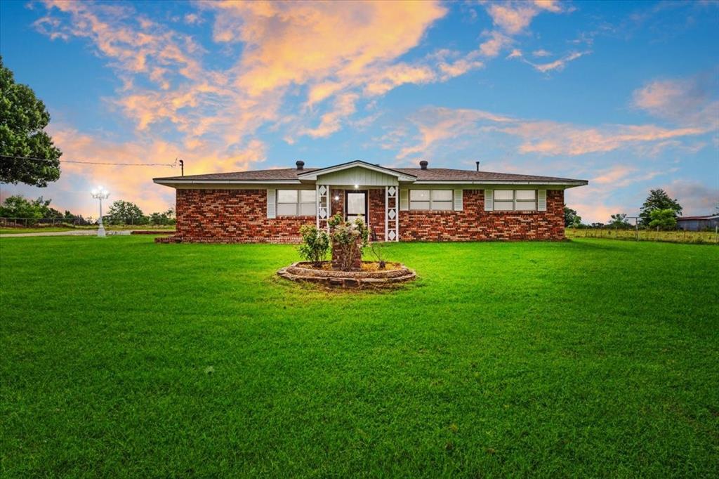 Escape to the tranquility of country living on 5 beautiful acres just outside Denison! This charming 3-bedroom, 1.5-bath brick home offers the perfect blend of comfort, functionality, and wide-open space. Inside, you'll find an inviting open floor plan featuring a spacious living room with a cozy propane gas-log fireplace, an eat-in kitchen with breakfast bar, double ovens, and ample cabinet space for entertaining and everyday living. The primary bedroom includes convenient built-in storage and a medicine cabinet, while the full bath features built-in cabinetry, and a relaxing garden tub. A separate utility room provides space for a freezer and additional storage. Outside, the possibilities are endless. The 5-acre property is fenced and ideal for outdoor recreation, gardening, or simply enjoying the peaceful setting. Additional improvements include a detached two-car garage, covered carport, storage buildings, and sheds for equipment and hobbies. Mature trees, open grassy areas, and a large backyard create the perfect backdrop for enjoying country sunsets.  Conveniently located with easy access to Highway 82, this property offers the privacy of rural living while remaining close to shopping, dining, and schools in Denison. Bring your vision and make this versatile acreage property your own!