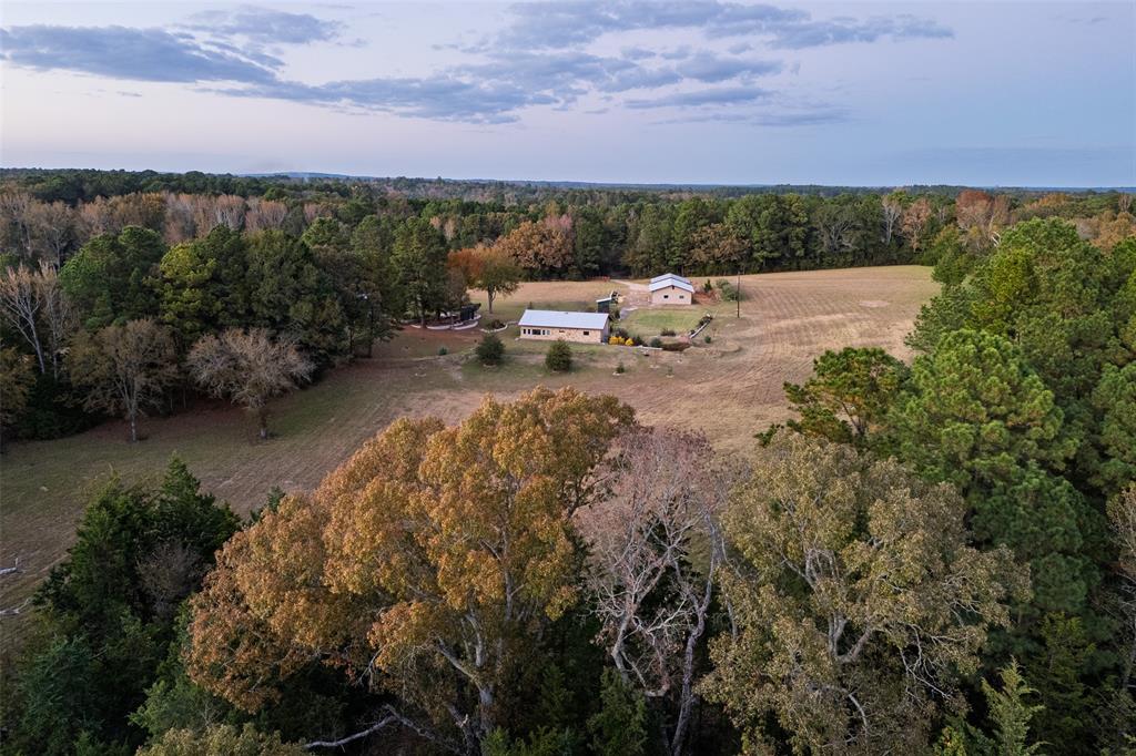 Bear Creek Ranch – Hunter’s Retreat with Home & Shop
Set back in the quiet Mixon community of northern Cherokee County, within Troup ISD. Bear Creek Ranch spans 36.91 acres of rare East Texas hunting ground. The 2-bedroom, 2-bath ranch-style home provides 1,640 sq. ft. of warm, functional living space, wrapped in a rock-and-metal exterior that settles naturally into the surrounding timber and gently rolling terrain. Bear Creek winds along the back of the property, watering the land and pulling in whitetails, hogs, and an array of East Texas wildlife. Backed by larger ranches and offering 600 feet of frontage on County Road 4910, this property delivers the rare combination of easy access and deep, quiet seclusion. The land is rich with character, towering hardwoods, cool creek bottoms, twisting draws, and a tucked-away slough that gives wildlife room to bed, feed, and roam. It’s the kind of ground hunters appreciate: varied, natural habitat with plenty of cover and movement. 
 Inside, the home is clean, bright, and welcoming, featuring tile floors, neutral tones, and an open layout that keeps the outdoors within view. The home was thoughtfully constructed of 2x6 wall for added durability and insulation keeping the elements out.  From the back room, look across the timber and catch steady deer traffic, or step outside and carve your own trails for hunting, ATV riding, or exploring. The area around the home is thoughtfully landscaped with mature trees, lush plantings, and garden areas for those who enjoy tending the land. A 1,200 sq. ft. shop stands beside the home perfect for equipment, tools, projects, or even a future bunkhouse conversion. A separate tractor shed and implement area sit away from the home, keeping gear organized without interrupting the natural setting.
Whether you’re after a weekend hideaway, a true hunting base camp, or a quiet rural homestead, Bear Creek Ranch brings together rustic charm, privacy, and East Texas outdoor living at its finest.