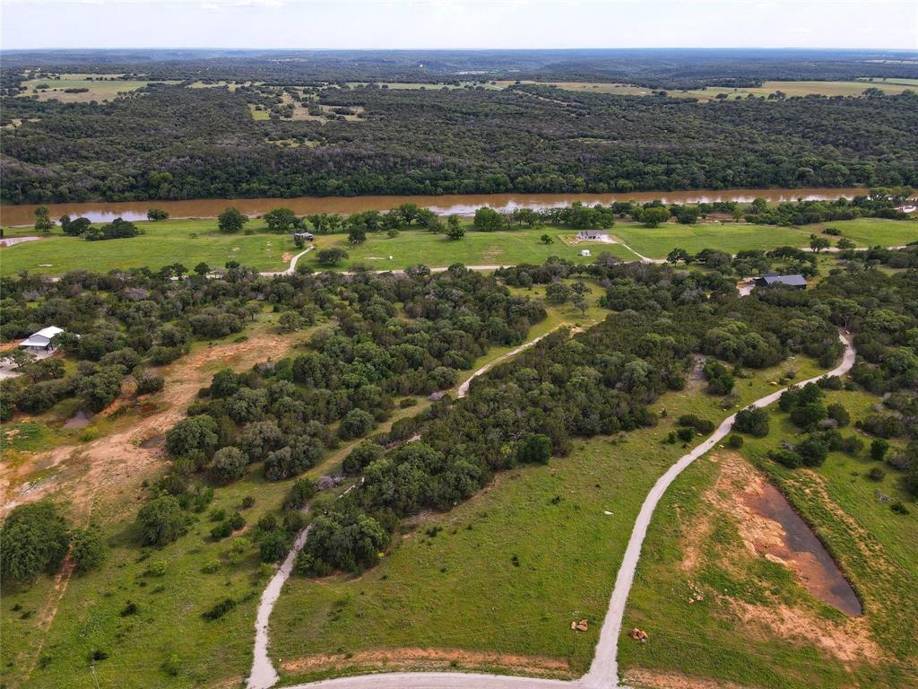 Discover the perfect blend of natural beauty and open space on this exceptional property—ideal for creating your dream home or a secluded getaway. Majestic, mature trees frame sweeping views of the Palo Pinto Mountains, while local wildlife and a private park on the scenic Brazos River offer unmatched outdoor enjoyment. With no HOA restrictions, you’ll have the freedom to shape the land to suit your vision. Continued membership in the local grazing association maintains the AG exemption, adding long-term value. Deed restrictions prohibit mobile homes, helping to preserve the area’s charm and property values. Whether you're seeking peace, adventure, or a lasting investment, this lot has it all.