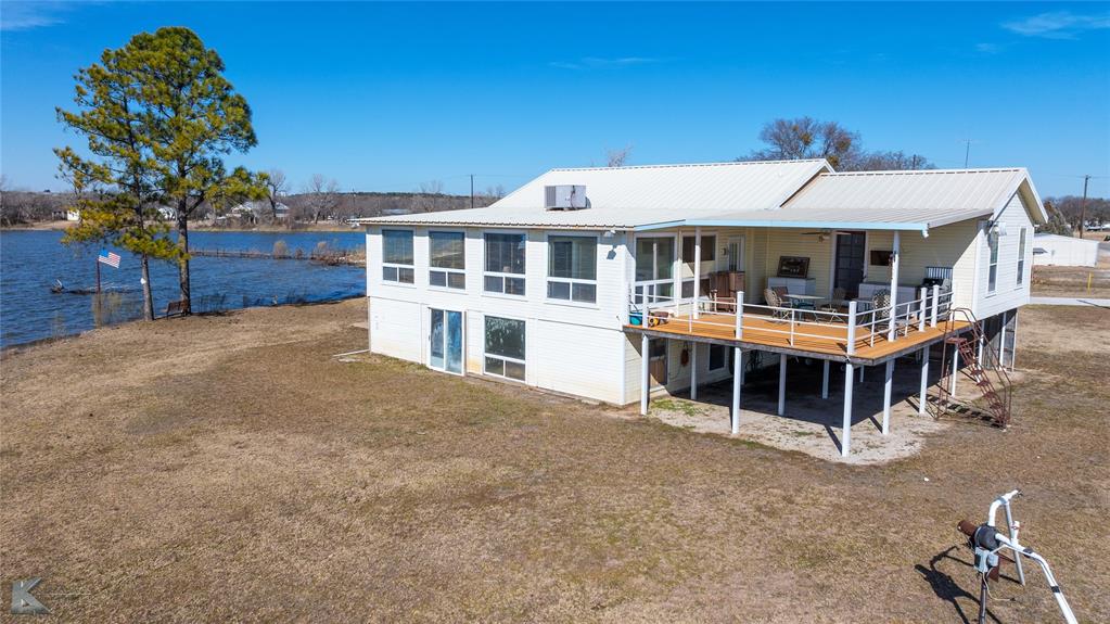 Motivated Seller! Lot is Owned. Above the Flood Plain. Flood insurance for this property is $419 per year.  Best elevated back porch view on the Lake!!! Charming Lakefront Retreat on Lake Leon. Discover your dream lake home at the end of a quiet cul-de-sac on beautiful Lake Leon in Eastland County. This elevated 2,166 sq. ft. property is designed for relaxation and entertainment, featuring 3 bedrooms, 4 full baths, and stunning panoramic views. Property Highlights include Spacious Open Floor Plan, Enjoy a seamless flow between the kitchen, dining, and living areas, enhanced by bay windows that frame breathtaking views of the lake. Updated Comforts, The home underwent complete plumbing and electrical upgrades 10 years ago, ensuring modern reliability. Covered Deck with Composite Flooring, Relax outdoors with durable composite flooring, metal pipe railing, and a covered outdoor kitchen, perfect for hosting gatherings or enjoying quiet evenings. Functional Features, The kitchen boasts a gas range with double ovens, while the separate laundry room and oversized closets provide ample storage. Flexible Living Arrangements, The home includes 2 bedrooms and 3 full baths in the main area, plus a separate bedroom with an en-suite bath accessible from the back porch. This layout comfortably sleeps up to 10 - 12 guests. Lakefront Access, The property’s lot is dock-ready, with the previous dock already removed, giving you a blank slate to design your own perfect boat dock. Storage and Parking, The enclosed storage space underneath the house complements a 3-vehicle carport and gravel driveway. Landscaping Options, The yard can be watered from the lake with a pump system, while city water supplies the home. Breathtaking Views, This south-facing home offers stunning sunsets over Lake Leon, visible from the bay windows or the covered porch. Whether you’re entertaining guests or enjoying a peaceful evening, the serene surroundings will leave you in awe.