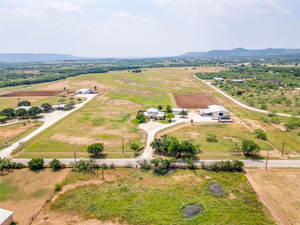 Set behind gated privacy and purpose-built for the serious horseman, this extraordinary 12.5-acre ranch delivers the complete roping lifestyle with premium improvements, exceptional functionality, and timeless Texas character. The striking two-story rock home features 3 bedrooms, 2.5 bathrooms, a brand-new standing seam metal roof, screened-in back porch, pergola-covered outdoor living area, and a welcoming circle driveway that creates an unforgettable first impression. A detached two-car garage with an attached 30x20 shop offers ample space for equipment, projects, and storage. Designed with competitors and horse enthusiasts in mind, the fully equipped arena is set up for both team roping and calf roping, featuring covered boxes, roping chutes on each end, pipe fencing, return alley, stripping chute with elevated platform, holding pens with automatic waters, and a layout built for efficiency and performance.  The horse barn is equally impressive with three pipe-and-creosote-lined stalls, insulated automatic roll-up doors on both ends, concrete center aisle, wash rack with floor drain, tack room, automatic waters, hay storage, and a lean-to providing additional covered parking. Built directly off the arena, the setup allows seamless movement from barn to practice pen.  The land is cross fenced into four separate pastures with quality pipe and cedar stay fencing, while the back pasture has been sprigged in highly desirable Tipton Bermuda. Ag exempt and meticulously maintained, this property blends luxury ranch living with a turnkey equestrian facility rarely found on the market.