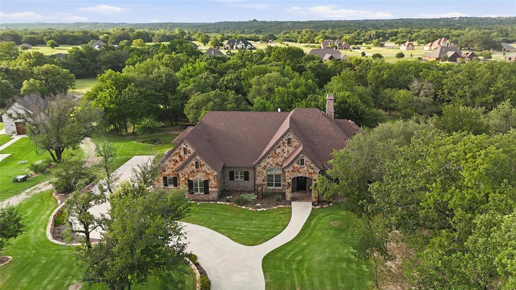 Truly one of a kind gated equestrian estate, where breathtaking Texas sunsets, exceptional craftsmanship, & thoughtful design create the ultimate country retreat. Situated on a picturesque homesite with sweeping views extending to the creek beyond, this stunning custom home by John Askew showcases extensive upgrades & remarkable attention to detail throughout. Step inside & be captivated by soaring ceilings, exposed wood beams, elegant arched openings, a dramatic floor to ceiling stone fireplace that anchors the spacious living area. Expansive windows frame stunning views of the outdoor living space surrounding countryside, seamlessly blending indoor & outdoor living. The luxurious primary suite is a private retreat featuring a spa inspired bath with a Hollywood soaking tub, oversized walk-in shower, dual vanities, abundant storage, a vanity area, a conveniently located sauna. The custom designed primary closet is truly exceptional. Designed for comfort & functionality, the home offers 3 spacious bedrooms, 2.5 bathrooms, a private office coffered ceilings and custom built-ins, a storage room, hidden safe storm room, oversized laundry room with built-in desk and sink, plus a mudroom.The chef’s kitchen is the heart of the home, offering abundant cabinetry, workspace, & an open flow into the breakfast area, making it ideal for everyday living and entertaining.Step outside to your own private paradise featuring an expansive covered outdoor living area with a wood burning fireplace, outdoor grill, sink, & breathtaking views. Whether hosting guests, enjoying morning coffee, or watching sunsets, this space is designed for year round enjoyment.Equestrian enthusiasts will appreciate the outstanding horse facilities, while the gated setting provides privacy, security, & the peaceful country lifestyle you've been dreaming of. Combining luxury, functionality, & incredible natural beauty, this extraordinary estate offers a rare opportunity to own a property that has it all.