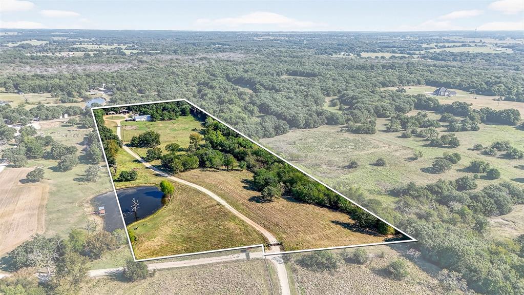 Discover 10.8 acres of beautiful North Texas land offering the perfect mix of mature oak trees, open space, and functional improvements. This property is ideal for those looking to build, expand, or create a private homestead with room to grow. The land features a balance of shaded areas and usable acreage, providing flexibility for livestock, gardening, recreation, or future development. A shared stock pond adds both scenic appeal and practical use, while the natural layout offers multiple possibilities for homesites, outdoor living, or additional structures. Well-equipped with valuable amenities, the property includes a private well house, greenhouse, storm cellar, and a two-bay workshop with electricity—perfect for equipment storage, hobbies, or small-scale operations. Covered RV and boat storage adds even more convenience for those needing space for recreational vehicles. A move-in-ready 3-bedroom, 2-bath home sits on the property, offering immediate use while you plan your long-term vision. With its combination of natural beauty, usable land, and existing infrastructure, this property delivers a rare opportunity to own acreage that’s ready to enjoy today and build on for the future—all while being conveniently located near nearby towns and amenities.
