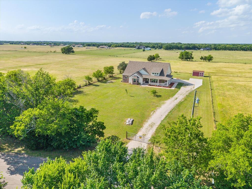 Town & country living at its finest awaits in this exquisitely crafted, like-new one-story brick home, perfectly positioned on a gated, tree-lined one-acre lot. Meticulously maintained & loaded with upgrades, this property offers the ideal blend of luxury, comfort, and privacy. From the moment you arrive, the stunning curb appeal & charming veranda-style covered porch create a warm & inviting first impression. Step inside to discover a thoughtfully designed interior where quality craftsmanship & attention to detail shine throughout. Elegant entry opens to a beautiful dining area & morning room, highlighted by a striking brick accent wall & custom mantel. Chef’s kitchen is truly the heart of the home, featuring an abundance of custom wood cabinetry with glass doors & interior lighting, granite countertops, a center island & stainless steel appliances—perfect for both everyday living & entertaining. Family room offers a dramatic floor-to-ceiling brick fireplace with premium Heatilator, providing both ambiance & exceptional warmth. Heated & cooled sunroom allows you to enjoy breathtaking rural views year-round. Unwind in the luxurious owner’s retreat includes cozy sitting area & a spa-inspired ensuite bath featuring a clawfoot soaking tub, oversized shower,& elegant chandelier. Additional bedrooms are generously sized with ample closet space & convenient access to full bath. Well-designed mud & utility room includes a custom drop zone, sink, & space for full-size washer, dryer, & additional refrigerator or freezer.  Two car garage offers built-in storage, while an extended concrete parking pad provides additional space for guests. Private backyard has plenty of room for a pool, garden, or outdoor oasis. Enjoy the peace and privacy of country living without sacrificing convenience—located just minutes from top-rated schools, shopping, dining, & major highways for an easy commute. This exceptional home truly has it all. Don’t miss your opportunity to make it yours!
