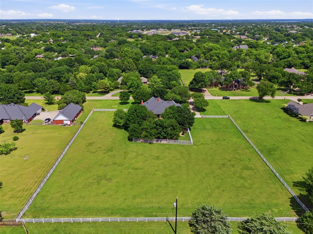Experience true freedom with this exceptional country estate in Lucas, TX. Situated on a peaceful cul-de-sac street, this property offers the perfect blend of rustic privacy and modern luxury. Horses are permitted on the property, and with no HOA, you enjoy total control over your land. Meticulously maintained by its original owner, this custom home sits on two acres of beautifully usable flat yard, providing an expansive canvas for animals, hobbies, or gardens. The main residence is designed for effortless daily convenience, functioning seamlessly like a single-story ranch. Inside, you will find durable, elegant custom tile flooring stretching throughout the entire home, ensuring a clean, hypoallergenic environment with absolutely no carpet. While daily life remains downstairs, the thoughtful layout features a private second level complete with an additional bedroom and an ensuite bathroom, making it an ideal retreat for guests, teens, or a quiet home office. Step outside into your personal backyard paradise, crafted for ultimate relaxation and entertainment. A refreshing saltwater pool serves as the centerpiece of the outdoor space, perfect for cooling off during hot Texas summers. You can entertain guests on the large, covered backyard patio or relax in the scenic pea gravel seating areas under mature, shady trees. Lucas offers premier acreage real estate within the highly rated Lovejoy ISD, allowing you to enjoy peaceful country nights while staying just minutes away from shopping, dining, and major highways in nearby Fairview, Allen and Plano. Buyer to purchase survey if required.