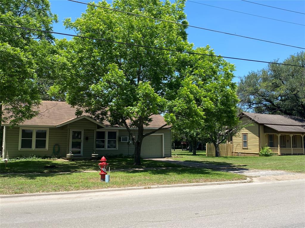 Solid built home with original wood floors and knotty pine paneling. The primary bedroom is large with two closets. The bathroom has been updated with new tile in the combo shower bath tub area. The kitchen has custom built cabinets and is large enough for an eat in kitchen. The back porch has been enclosed to make a great mud room and laundry area. The Living Room is spacious with a decorative fireplace as it was capped off years ago. There is a plug next to the fireplace to add a faux electric heater fireplace. There are 3 gas space heaters and 2 wall unit air conditioners that keep the home cozy year round. There is an oversized one car garage with room for a workshop or storage. This home sits on a quarter acre lot with a nice deck on the back to enjoy a shaded back yard with a mature producing pecan tree. Directly behind this home is a one acre fenced parcel of land that is also included with this listing along with a second home or guest quarters next door. This package deal with the small yellow house next door and the one acre parcel of land behind adds up to 1.5 acres. The small yellow home needs has sheetrock but needs renovations completed. Bring your imagination - the historic yellow home would make an awesome B&B.