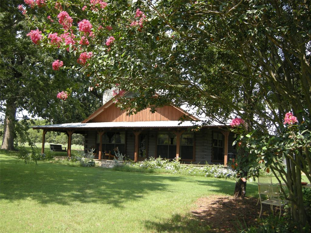 MOTIVATED SELLER doesn't want you to miss an opportunity to see this beautiful property! Charming SATTERWHITE LOG HOME on 130+ rolling acres. Stunning setting is ideal for those looking to escape to the country, start a farm or ranch, or simply enjoy the peace and beauty of East Texas.  Property includes log home, workshop-barn, hay barn, well, corral, fenced & crossed fences, 5 ponds-lake, rolling hills, well for watering garden and so much more! One lake is 5+ ac. Home features an expansive covered porch & enclosed back porch, ideal for taking in the breathtaking countryside views.  Inside, you’ll find a warm and inviting living space with a gorgeous stone fireplace, large windows, 4 comfortable bedrooms, plus hall cedar closet. Spacious kitchen with eat-in dining rm, huge laundry-storage rm plus ample storage throughout.  Maintenance is easy with stained concrete flooring.  Wood ceilings & walls create a cozy vibe!  Property includes two large barns that are perfect for storing equipment or serving as workshops. Whether you’re looking to expand your agricultural operations or need space for hobbies and projects, these barns provide the room you need.  The property is equipped for ranching, self-sufficiency & reliability with a greenhouse, generator and propane storage. Water is plentiful, with 5 ponds and a well that provides garden irrigation.  A propane tank and generator ensure reliability.  The property has approx 3000' of road frontage providing great access.  Additional features include a two-car carport and lots of storage off the enclosed patio.  The land is currently leased for cattle. There is the potential for continuation of the lease, making this an excellent investment for ranchers or those seeking a peaceful retreat with income potential.  Land is a mix of open pasture, wooded areas and ponds.  The land & buildings on this ranch are very well maintained. Spend hours exploring trails & gorgeous sunsets! Award Winning Lindale ISD. A Real E Texas GEM!