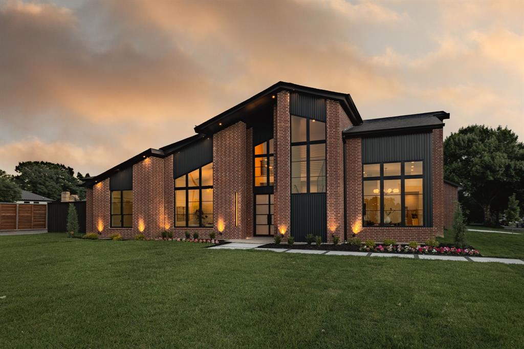 Newly completed in 2026 by Chris Sandlin Homes, this modern, mid-century–inspired residence delivers 5 bedrooms, 5.5 baths, and approximately 5,200 square feet on a half-acre corner lot with a 3-car garage. A striking facade pairs warm brick with dark metal accents and expansive black-framed windows, setting the tone for the light-filled interiors behind steel-and-glass entry doors. The main level is designed for easy everyday living: a sunlit foyer with open stair, a glass-door study, corner dining wrapped in floor-to-ceiling windows, and an open kitchen and living area centered by a marble-clad fireplace with walnut built-ins. The showpiece kitchen combines custom walnut cabinetry with rich green uppers, Calacatta-look quartz surfaces, a waterfall island, designer pendants, and a walk-up wet bar with beverage fridge. Solid white-oak floors and curated lighting carry throughout. Two bedrooms sit downstairs, including a vaulted primary retreat with backyard access. Its spa bath features a fluted soaking tub, glass-enclosed shower with full-height stone slabs, and dual vanities; the custom closet connects directly to the main laundry. Upstairs offers a large game room with beverage bar, three ensuite bedrooms, a second laundry, and a fully insulated walk-in attic for effortless storage. Outdoor living includes a deep covered patio with summer kitchen and gas fireplace overlooking a pool-ready yard. Quality construction and energy-minded systems provide comfort and peace of mind: engineered foundation, foam-insulated envelope, premium windows and wide sliders, tankless hot water, efficient multi-zone HVAC with smart thermostats, EV-ready power, and prewire for security, whole-home audio, and motorized shades. Central Dallas location places dining, parks, and top schools within easy reach. Move-in ready and meticulously finished.