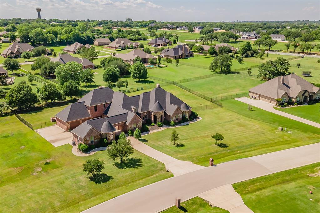 Discover refined luxury in the gated community of Rose Creek Estates, perfectly situated on over 1 acre in Mansfield ISD. This exceptional two-story estate offers 5 spacious bedrooms, 7 bathrooms, study, and guest quarters, blending elegance, comfort, and thoughtful design throughout.

Step inside to an open-concept layout filled with natural light and accented by timeless details. The gourmet kitchen is a true centerpiece, featuring bespoke cabinetry, an expansive island, gas cooktop, stainless steel appliances, and a walk-in pantry—ideal for both everyday living and entertaining. The adjoining dining area and formal living provide the perfect setting for intimate dinners or larger gatherings.

The private primary suite is a true retreat, complete with a luxurious ensuite featuring a fireplace, soaking tub, separate shower, and dual vanities. Each additional bedroom offers walk-in closets, en-suite bath, and custom finishes, ensuring comfort and functionality for all.

Designed for both relaxation and entertaining, the outdoor space showcases a beautifully landscaped backyard, covered patio, and a striking stone patio perfect for enjoying peaceful surroundings year-round. Exterior stone accents enhance the home’s curb appeal and create a commanding presence within this sought-after gated community.

Additional highlights include generously sized living areas, an oversized 3-car garage, additional parking for 2 vehicles, a versatile floorplan, and a separate guest house with a full bedroom, kitchen, living, and bath.
This remarkable property offers the perfect balance of privacy, space, and convenience—truly a lifestyle opportunity.