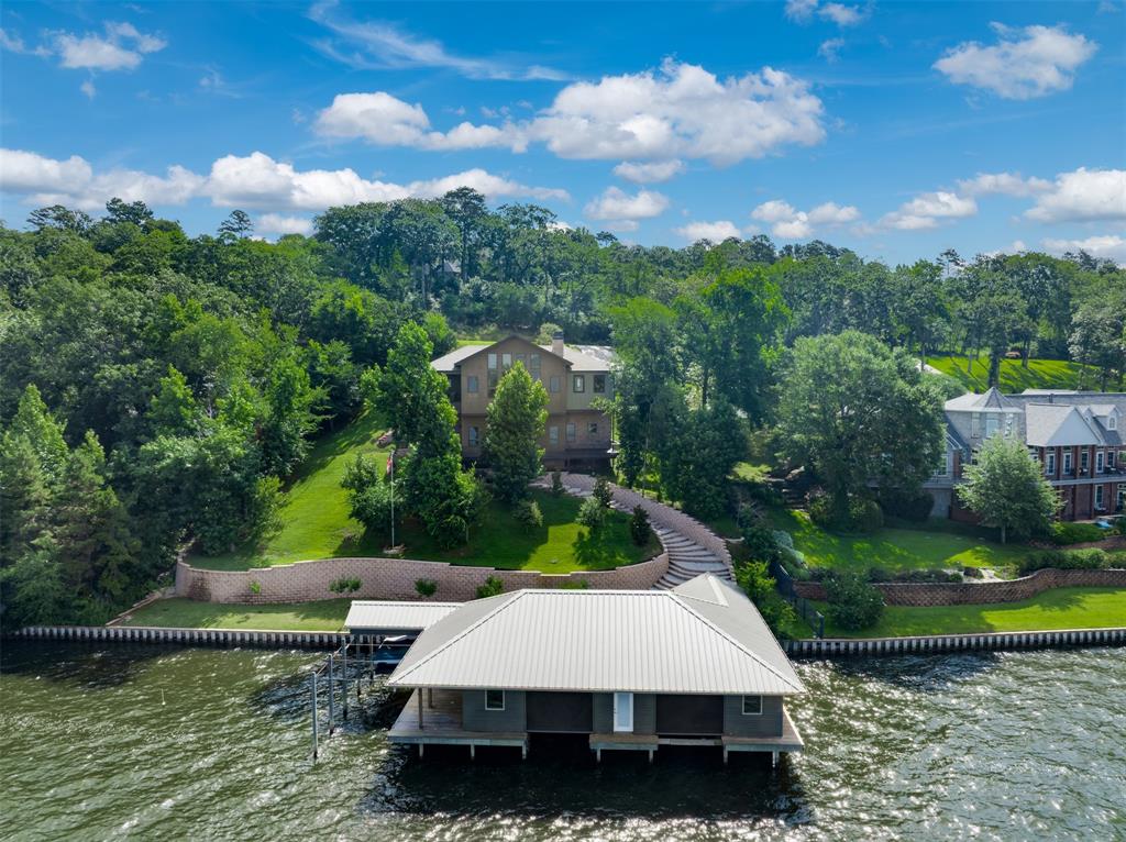 The ultimate in quality construction perched on the bluff in the prestigious Eagles Bluff gated golf course community on beautiful Lake Palestine, this custom-built, energy efficient waterfront home with a 2,200 sq. ft. boathouse represents the pinnacle of luxury engineering. Combined with dramatic architecture with deep-bedrock anchoring, this home safely delivers unobstructed, panoramic views. extensive drainage and retaining walls to ensure that quality remains in this stunning home for years to come. The open floor plan with tall ceilings features a wood burning fireplace, Alder wood cabinets, Alder wood doors and trim, Hickory hand-finished floors, Italian tile floors and Marvin Elevate Casement windows. This 3 bedroom, 2 ½ bath home has 2 living areas all with beautiful views of the lake. There is also a 50 yr. asphalt roof, and a full-house generator - plus 220-volt outlets in garage for electric vehicles or hobbies. The boathouse with cypress nickel gap-siding contains a kitchenette, water filtration system, and an outdoor grilling area along with 2 full-size slips with boat & jet ski lifts, glass garage doors, with solar shades. Eagles Bluff is a family-oriented gated community with a Carlton-Gibson designed 18-hole golf course, double-sided driving range, resort style pool, tennis and pickle ball courts, fitness center and clubhouse with fine and casual dining. Come and enjoy the beautiful sunsets.