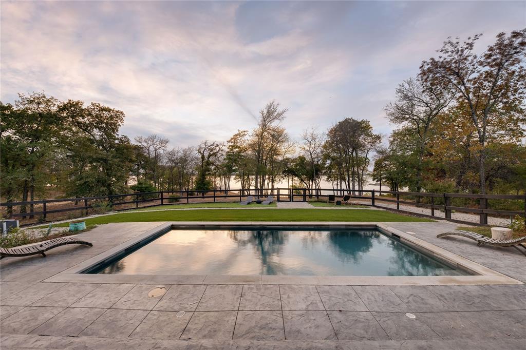 Welcome to 1180 Oak View Ct. in the revered Eagles Landing subdivision. Nestled on 1.7 acres with significant Lake Lewisville frontage, this colonial masterpiece radiates New England allure. Merely 2 miles from both the polo and yacht clubs, it's positioned for the discerning enthusiast. Crafted for lakefront elegance, interiors showcase design celebrating water views. Dual offices and two primary suites—one on each floor—cater to luxury and seclusion. The upper screened patio is a sanctuary for yoga, sipping wine, or reflecting by the lake. The 5th bedroom's adaptability makes it apt for media or play, and generous storage graces the home. It stands out in energy efficiency thanks to foam insulation. Outside, an inviting pool, outdoor shower, and verdant gardens with fresh produce await. A private beach and rock perch provide peaceful lakeside respites. 1180 Oak View Ct. isn't just a residence; it's an embodiment of upscale living, blending luxury, accessibility, and nature.