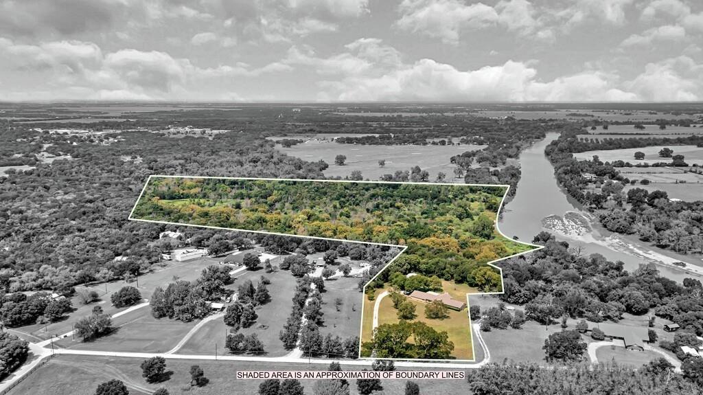 Along the banks of the Brazos River, life slows down a little on this 36-acre piece of Texas ground. Here, wide pastures roll into shaded woods, and pecan trees stand steady through the seasons. Nearly 1,122 feet of river frontage stretches across the back edge of the property, offering space for fishing, hunting, or simply sitting still while the water carries the day away. The land holds an ag exemption and plenty of room for horses, livestock, or recreation.
The home is a one-story brick ranch from 1976, built solid with four bedrooms and two and a half baths. At its heart, a wood-burning fireplace waits for cool evenings, flames dancing against a brick hearth that’s warmed many gatherings before. The kitchen looks out toward the pasture, and the laundry room is more than just laundry — it’s a work space with cabinets, counters, a sink, and room for sewing or canning or storing what needs to be put by. Out back, a pergola stretches over the patio, a shady place to sit and breathe in the wide Texas sky.
A workshop with electricity stands ready for projects, and the property includes city water, septic, and an existing well not currently in use. Trails wind through native growth toward the river, while the home site itself sits high and secure, away from flood concerns. Just minutes from town, tucked in Bosqueville ISD, it’s the kind of property that gives you both connection and retreat. Out here, the pace eases, the stars shine brighter, and the river keeps rolling, same as it always has.