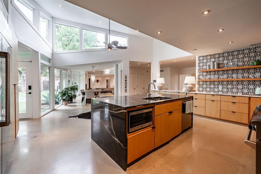 Step into modern luxury with this beautifully transformed Tittle-Luther mid-century classic. Located on a quiet, tree-lined corner lot in the heart of coveted Elmwood, this incredible home sits on a perfectly manicured 0.4-acre private estate and delivers approximately 4,509 square feet of clean detail. Natural light pours through walls of glass, highlighting the signature clean lines and premium finishes that define every room. The show stopping kitchen was built for serious cooking and gathering, see rich white oak cabinetry, floating shelves, sweeping marble surfaces, a oversized island, a walk-in pantry, and premium appliances. The primary suite is a true sanctuary, offering nearly 1,000 square feet of peaceful retreat complete with a fireplace, spa bathroom featuring a deep jacuzzi tub, and a secluded courtyard just steps away. A sophisticated media room with a full bar looks into the backyard, creating the perfect vantage point for the outdoor escape beyond.
The fully walled grounds feel like your own private getaway: a custom pool and spa, built-in outdoor kitchen and bar, expansive turf lawn, and striking evening lighting that sets the stage for unforgettable gatherings. Additional features include four bedrooms, four full bathrooms, plus a self-contained guest wing with kitchenette, living space, and private bath, smart home systems, multiple fireplaces, soaring vaulted ceilings, and plenty of oversized parking. Originally constructed in 1950 and meticulously updated with care, this hidden oasis delivers rare privacy and modern comfort in Abilene ISD.  Perfect for those who want to live exceptionally in West Texas.