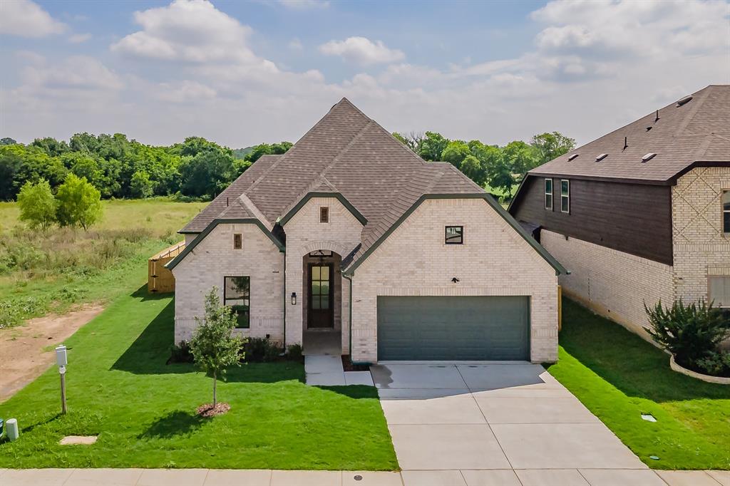 Welcome to this stunning brand-new brick home perfectly situated on a spacious quarter-acre lot backing to peaceful green space, offering the ideal combination of privacy, luxury, and convenience just 15 minutes from downtown FW. Boasting 4 bedrooms, 3 full baths, & 2,298 square feet of thoughtfully designed living space, this home features a bright and open floor plan with soaring ceilings and high-end finishes throughout.
From the moment you arrive, you'll appreciate the upgraded front door, beautiful curb appeal, and attention to detail. Inside, the spacious living room serves as the heart of the home, featuring custom built-in cabinetry, sleek electric fireplace, & a modern oversized ceiling fan. The chef-inspired kitchen is sure to impress with a massive quartz island, abundant cabinetry, breakfast bar, pantry, and sunny breakfast nook, making it perfect for both everyday living and entertaining. The luxurious primary suite offers a private retreat complete with a tray ceiling, crown molding, ceiling fan, dual vanities with quartz countertops, freestanding soaking tub, and an oversized walk-in shower featuring a rainfall showerhead, built-in bench, and designer niches. The large walk-in closet includes custom shelving for exceptional organization. Secondary bedrooms are generously sized and equipped with ceiling fans, while the guest bathrooms showcase quartz countertops, built-in cabinetry, and beautifully tiled shower-tub combinations with decorative niches. Additional upgrades include crown molding throughout, elegant window trim, a well-appointed utility room with built-in cabinets, countertop workspace, and sink, gutters, and an electric vehicle charging station installed in the garage. Step outside to enjoy the covered back patio overlooking the tranquil green space, surrounded by attractive wood and wrought iron fencing. Combining modern style, quality craftsmanship, and an unbeatable location, this exceptional home is ready to welcome its first owners.