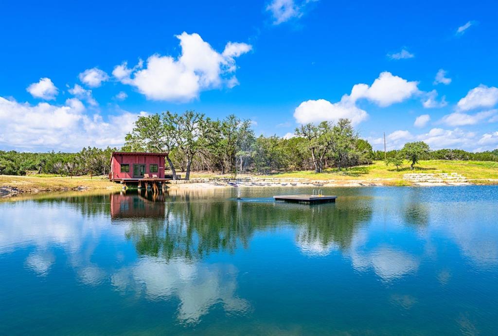 In the heart of Texas Wine Country near Fredericksburg, 260 Acres, Parked Out, Pond, Multiple Improvements & Off-Grid Capable. Welcome to Lonesome Valley, a stunning 260-acre Hill Country ranch in the heart of Texas wine country. Ideally located just 30 minutes west of Dripping Springs, 9 miles west of Johnson City on Hwy 290 and only 1.5 miles from the gate via Rocky Creek Road, this private estate offers a mile-long paved drive to the main improvements. The ranch features breathtaking views, mature oak trees, rolling hills, large open pastures, and wooded areas for wildlife habitat. Wildlife includes whitetail deer, axis, turkey, dove, and hogs—making it a hunter’s paradise. Approximately half of the ranch is cleared while the other half remains natural. Improvements include a 3-bed, 3-bath main home with a large covered outdoor kitchen-living area offering incredible views. A spacious barndominium includes a 3-bed, 3-bath upstairs with a 10-bed bunk room, and downstairs features a full kitchen, bath, saloon, and living area—all with wraparound porches. Amenities include a large fire pit, basketball, tennis, and two pickleball courts. There’s also an equipment barn with a small apartment. A 2 bedroom, 1 bath fishing cabin overlooks a 1-acre pond with a pier, fountain, floating dock, and man-made creek. The ranch also includes a seasonal creek, extensive trails, and a high-fenced garden. Off-grid capable, the ranch is powered by solar, 100,000-gallon rainwater collection, deep well, backup generators, wood stoves, and 4,000 gallons of propane. Underground electricity is in place. Lonesome Valley is a turnkey family retreat with income potential from Airbnb, weddings, and corporate events. In Q4 of 2024 alone, Airbnb rentals brought in over $30,000. Offered fully furnished, with a replacement value of apx $10M. Potential for 3,000 ft airstrip. *Financing available *Owner-Agent