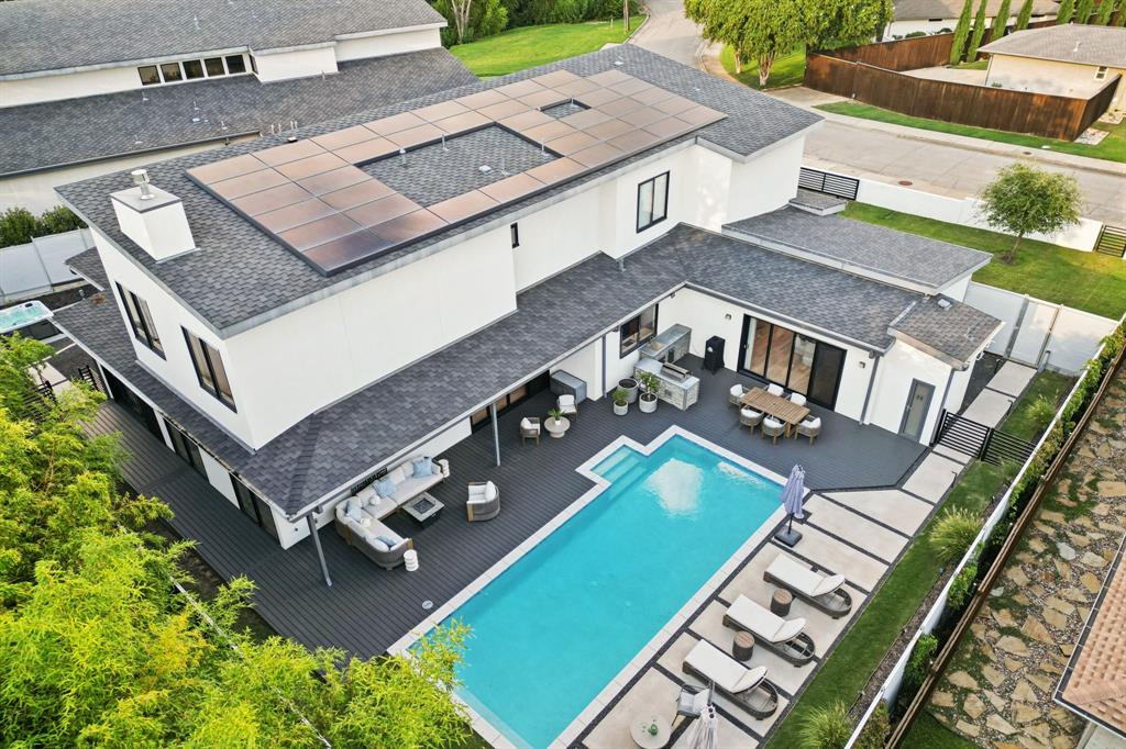 Modern presence meets private seclusion just minutes from the heartbeat of Dallas. Whether you’re seeking quiet moments of solitude or lively gatherings with family and friends, this refreshed and refined home delivers on every level. From the moment you arrive, bold architectural lines and striking materials—crisp stucco, luxe stone, and a glass-paneled garage door—set the tone. A private gated drive welcomes you into a residence where sleek design and cutting-edge technology define the experience. Inside, light and luxe finishes blend effortlessly with warm wood tones and next-level amenities. The designer kitchen balances elegance and function with a hidden walk-in pantry, full-size wine refrigerator, and seamless flow into the dining and living spaces, tailor-made for effortless entertaining.
Expansive glass doors open to your personal resort: a NEWly crafted deck along with “grill-and-chill” outdoor kitchen, sparkling pool for sun-drenched afternoons or glowing night swims, and an adjacent spa just steps from the primary suite, perfect for late-night soaks under the stars. The smart pool system manages heat, cleaning, lighting, and winter protection right from your phone. The main level features a serene owner’s suite, private study, and light-filled guest room, each with spa-inspired ensuite baths. Upstairs offers three more ensuite bedrooms and a generous flex space with bar, ideal for movie marathons, game nights, or creative pursuits. Tech-forward living includes automated shades, owned Tesla solar panels, Tesla EV charger, and a whole-house alkaline water filtration system, designed for a healthier, smarter lifestyle. Style. Seclusion. Sophistication. Welcome to your Dallas dream!