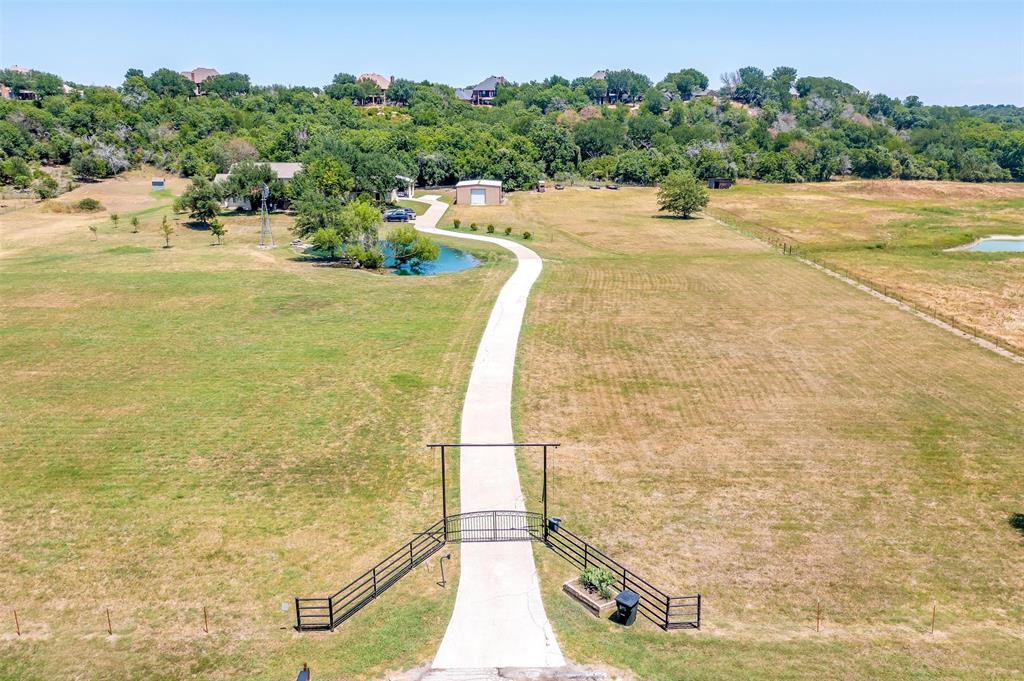 Welcome to an exquisite sanctuary nestled in the heart of Aledo! This modern +-3,904 square foot residence boasts a perfect blend of elegance and comfort, spread across +-10 lush acres. Four spacious bedrooms and three luxurious bathrooms, designed to cater to your every need. Upon entering, you're greeted by expansive living spaces adorned with contemporary finishes that seamlessly blend with the serene natural surroundings. The gourmet kitchen, equipped with top-of-the-line appliances and sleek countertops, is a chef's dream come true. Oversized master suite with en-suite bath and walk-in closet. Step outside to discover your personal oasis: a shimmering pool invites you to unwind, while two tranquil ponds provide a picturesque backdrop for outdoor gatherings and moments of reflection. The sprawling grounds offer endless possibilities for recreation and relaxation. A +- 1200 square foot shop offers space for livestock, storage, or equipment. Experience the epitome of modern living in a setting that offers privacy and peace. This is more than a home; it's a lifestyle.