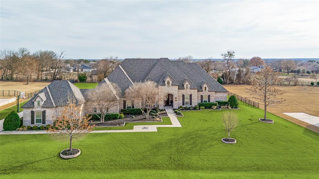 Welcome home to this stunning Prosper estate, custom built by Dave R. Williams. Tucked inside the exclusive gated community of one-acre homesites in Christie Farms, this property blends elevated design with everyday warmth while offering exceptional privacy and serenity.

An expansive entry creates an immediate sense of arrival, leading to a beautiful formal dining room perfect for gatherings. The main living area impresses with soaring ceilings, handcrafted beams, and walls of windows that flood the space with natural light. Grand in scale yet inviting in feel, it’s designed for both entertaining and comfortable daily living.

The kitchen is a true showpiece and the heart of the home. It features a professional-grade Sub-Zero refrigerator and premium appliances by Wolf, including a six-burner gas range, double ovens, and built-in microwave. A spacious walk-in pantry keeps everything organized behind the scenes.

With five bedrooms and five-and-a-half baths, the layout offers thoughtful separation and flexibility. The primary suite is privately situated on its own wing, creating a true retreat with direct backyard access and room to unwind in comfort. On the opposite side, three guest suites sit behind a sliding barn door, each with its own en suite bath. A built-in desk nook adds convenience for homework or projects. Just beyond the main living area, a fifth bedroom offers versatility as a second primary suite, in-law quarters, or flex space. A dedicated office and media room complete the interior, offering space to work, relax, and entertain with ease.

Step outside to an entertainer’s backyard featuring a built-in gas grill, outdoor fireplace, expansive covered patio, sparkling pool, and a massive grassy yard rarely found in luxury properties, all set on a private one-acre lot.

Located in a prime Prosper setting within a highly sought-after school district, this home delivers custom craftsmanship, exclusivity, and refined luxury living.